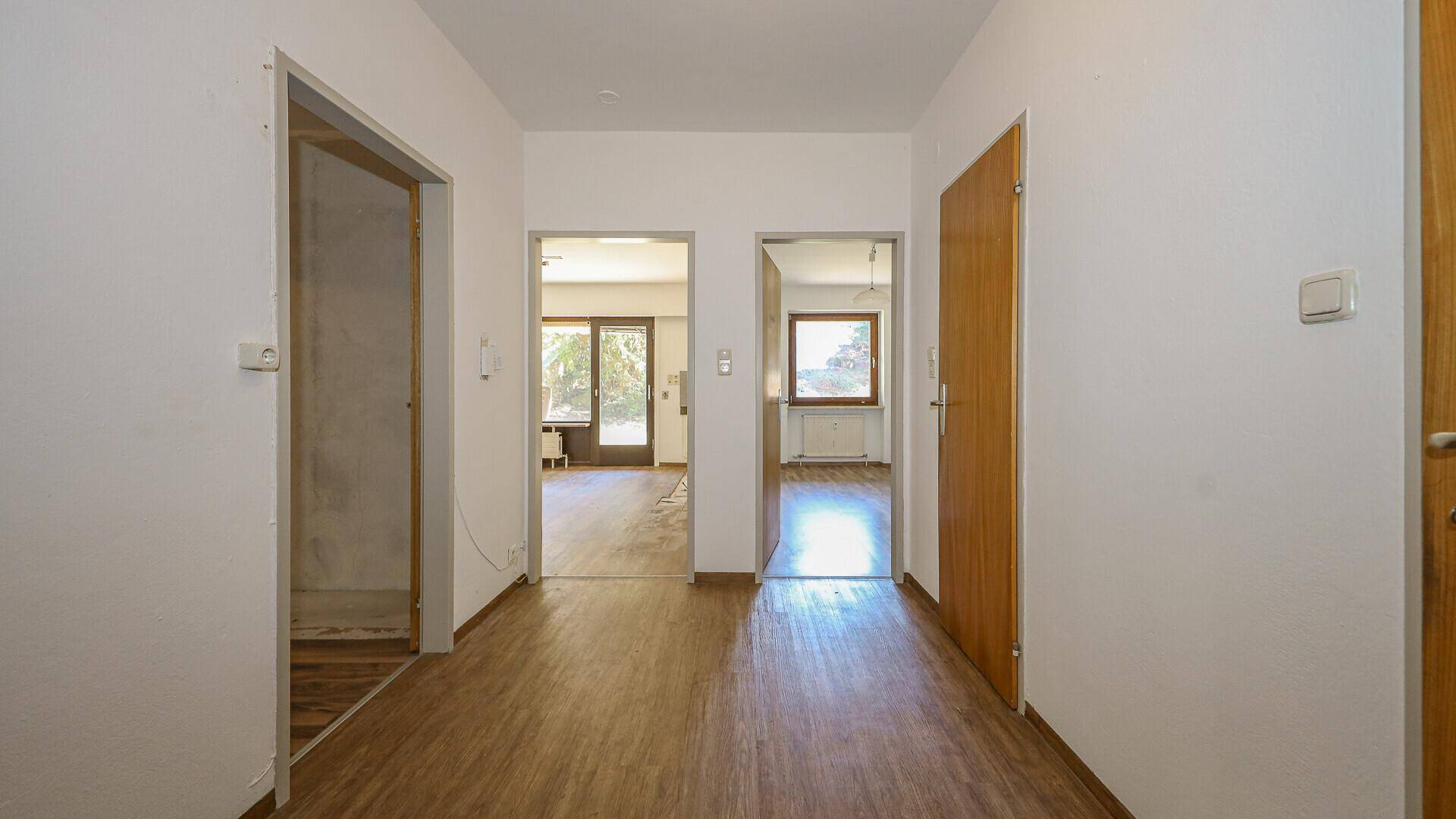 Heller Flur mit Holzboden und Türen, die zu verschiedenen Räumen der Wohnung führen.