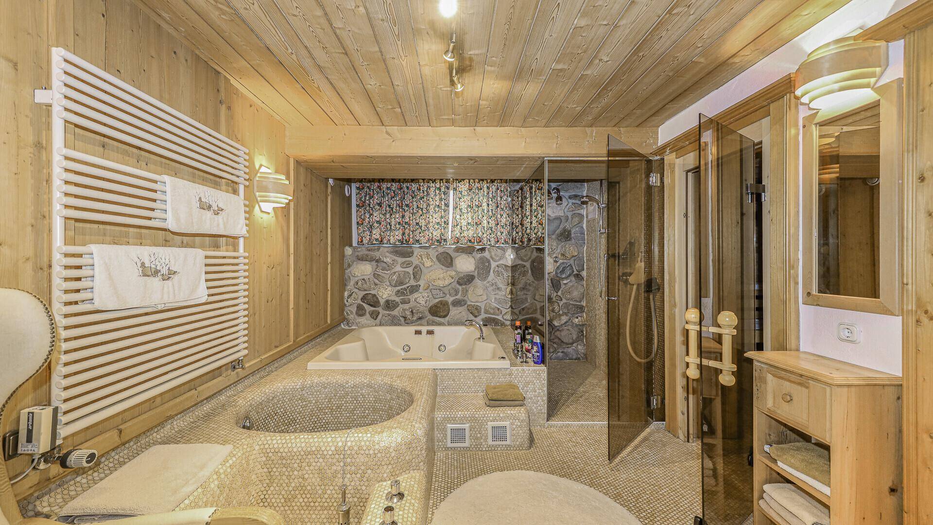 Exklusives Badezimmer mit Whirlpool, Dusche und Sauna im Wellnessbereich.