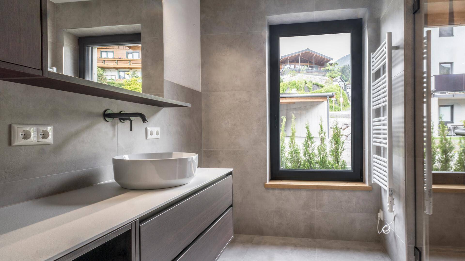 Helles Badezimmer mit modernem Waschbecken, beheiztem Handtuchhalter und Fenster.