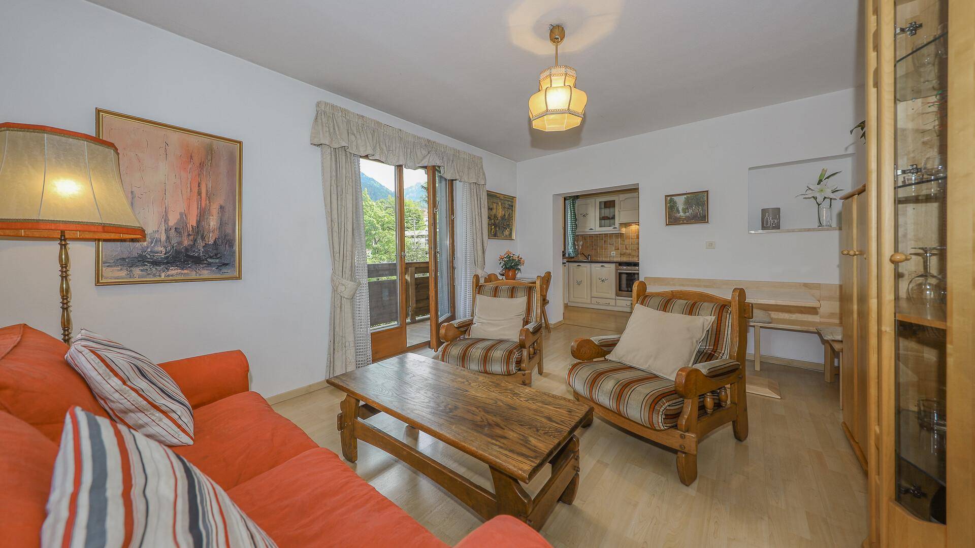 Helles Wohn-Esszimmer mit traditionellen Holzmöbeln und Balkonzugang.