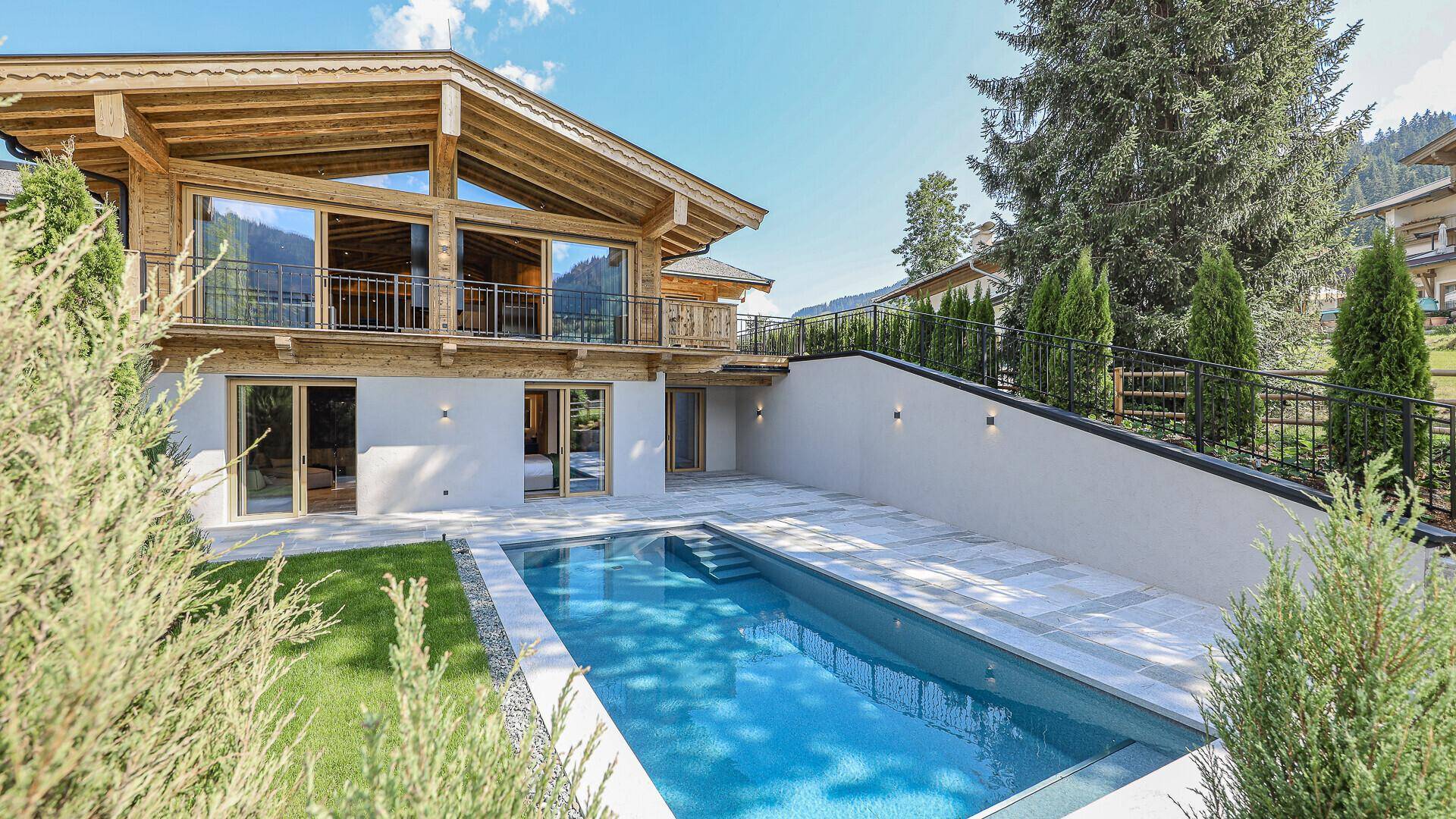 Privater Außenbereich mit Pool, gepflegtem Rasen und moderner Architektur des Chalets.