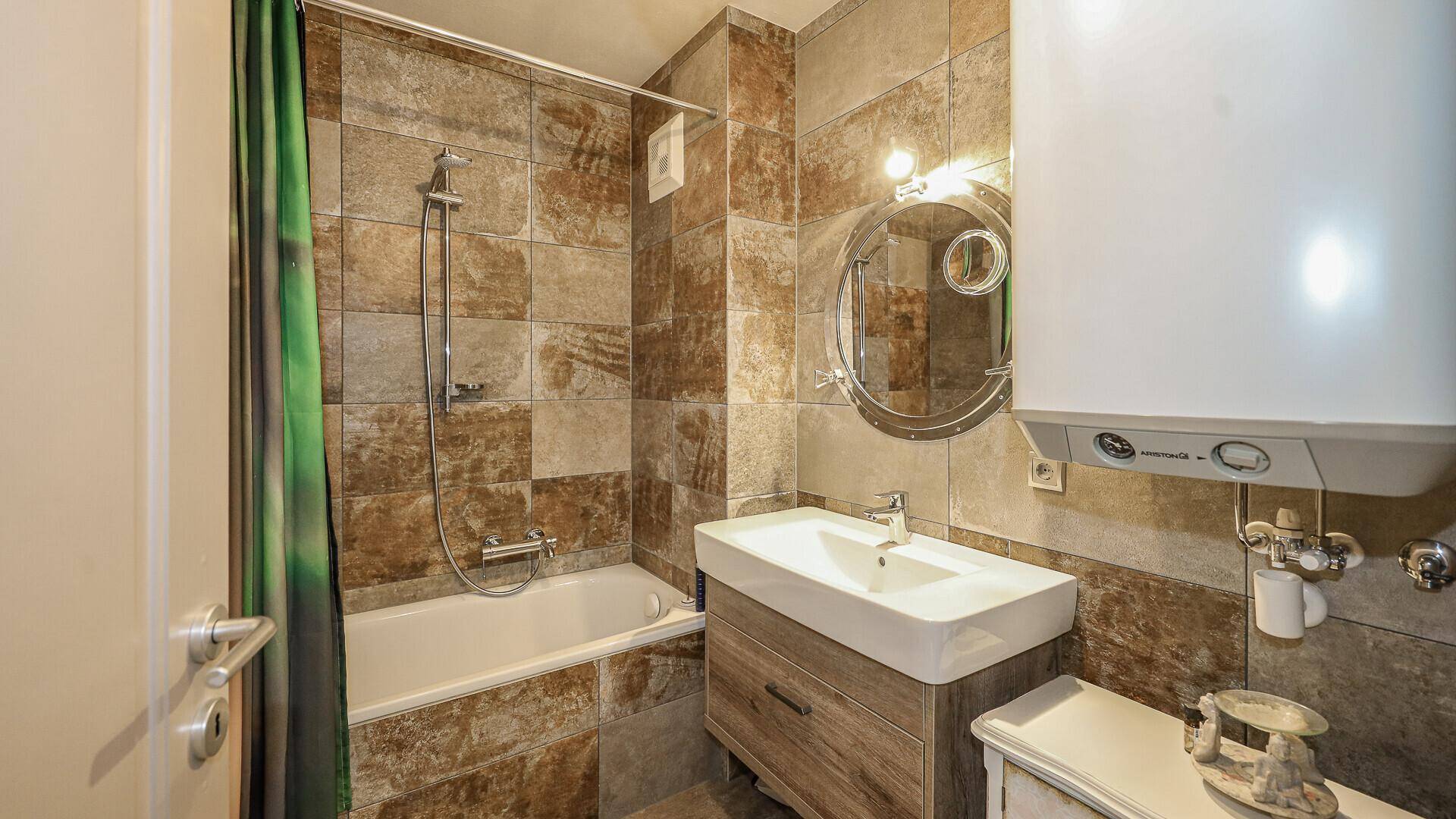 Badezimmer mit Badewanne, Waschtisch und Fliesen in Erdtönen.