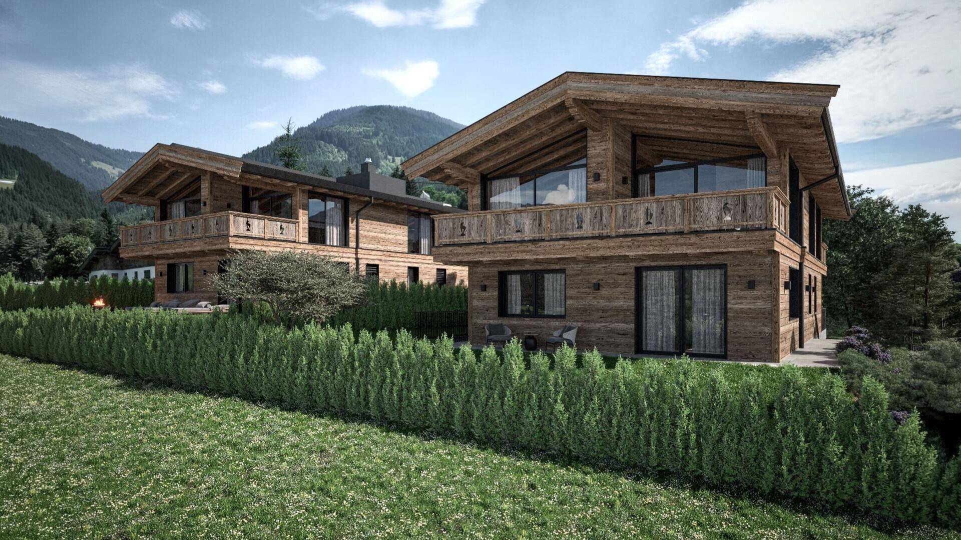 Zwei moderne Chalets in Holzbauweise mit Bergblick und gepflegter Hecke in alpiner Landschaft.