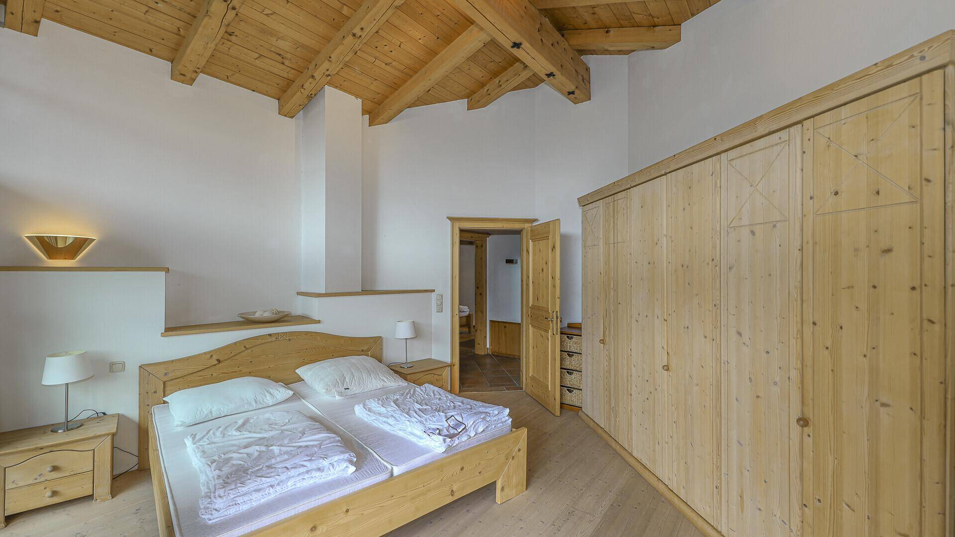 Helles Schlafzimmer mit Holzbalkendecke, traditionellem Bett und geräumigem Kleiderschrank.