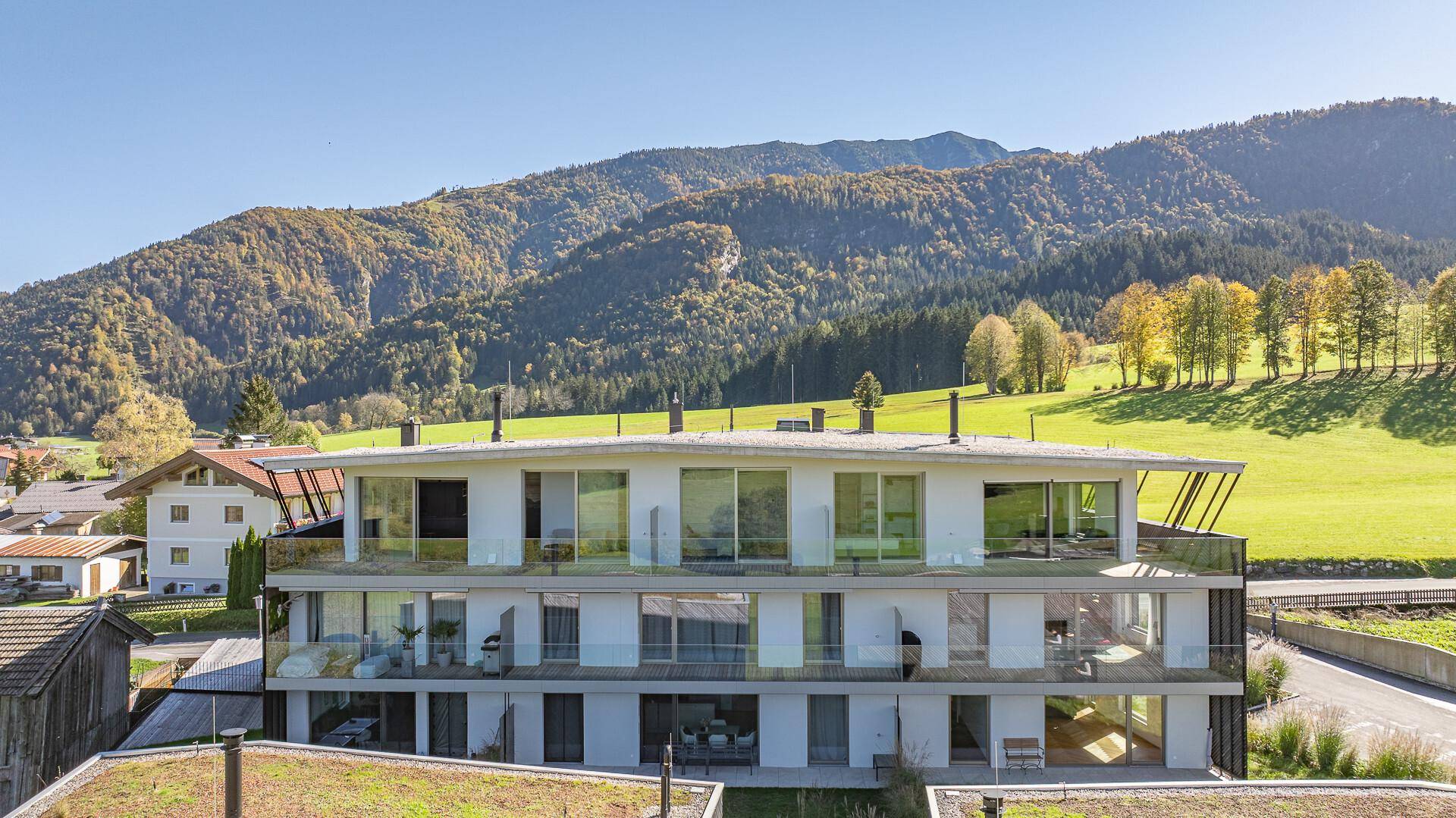 Ansicht der modernen Wohnanlage mit weitläufigen Balkonen und Panoramablick auf die Berge.