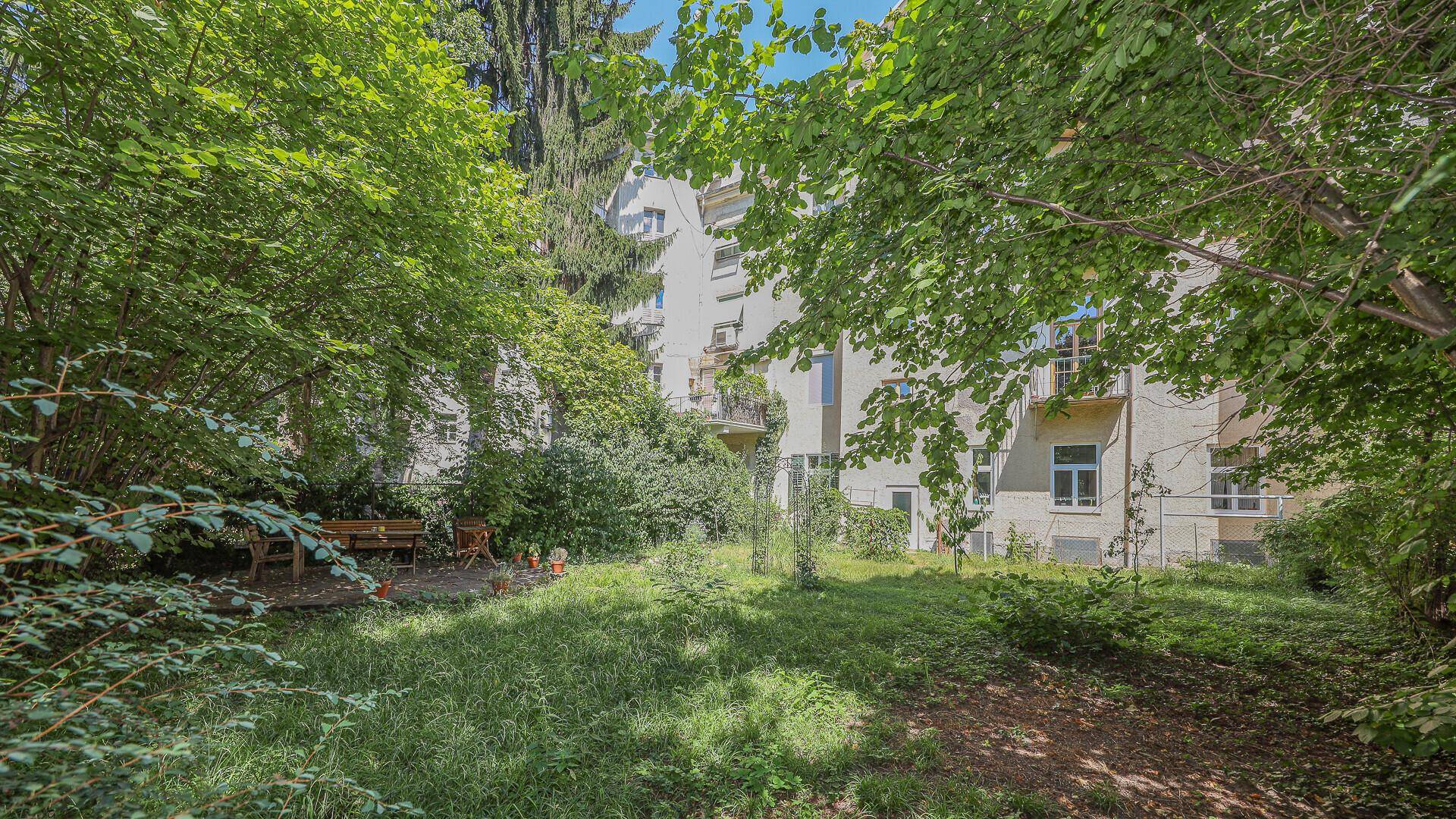 Weitläufiger Garten mit viel Grün und Blick auf die umliegenden Gebäude.