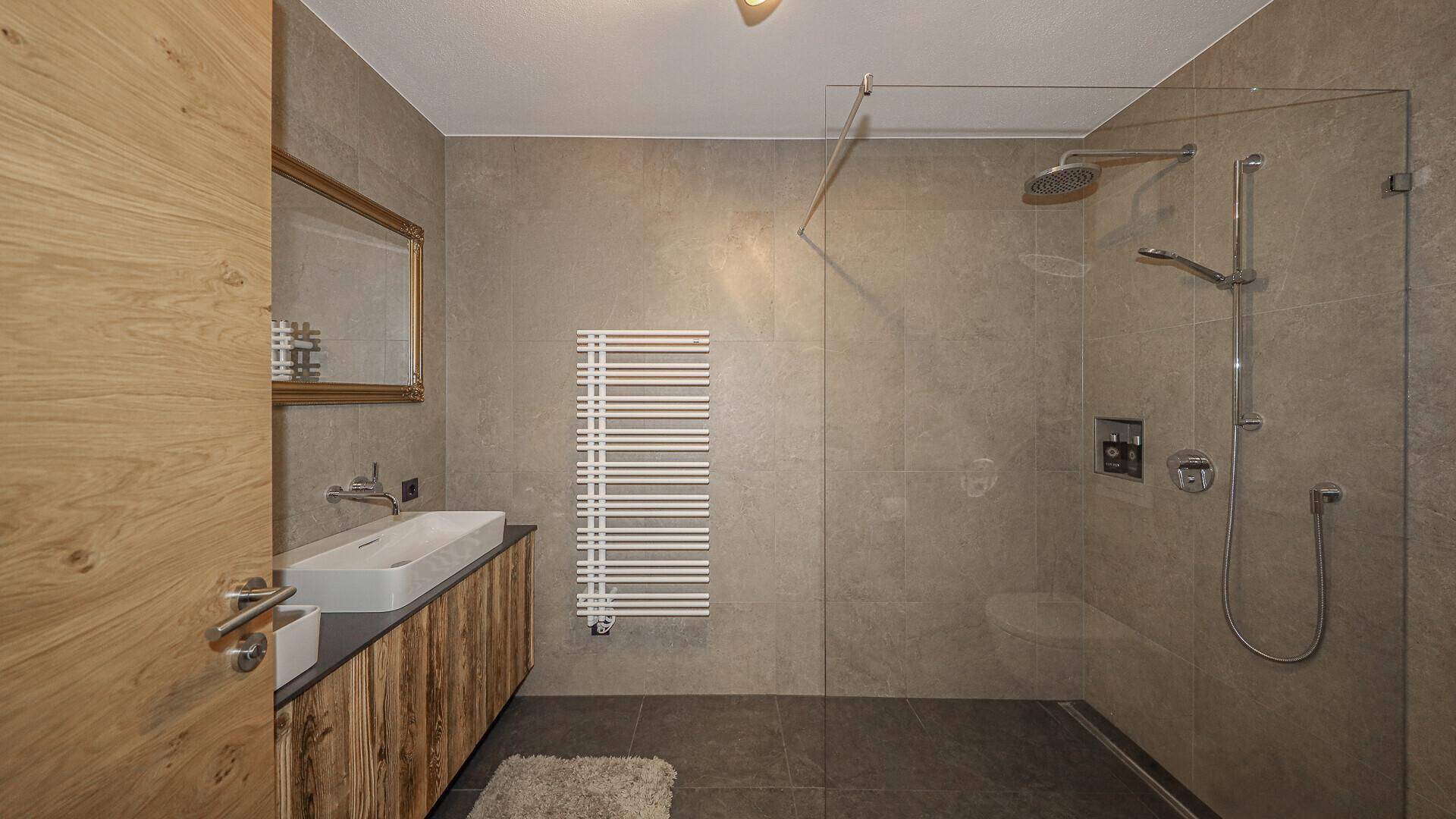 Modernes Badezimmer mit begehbarer Dusche, Einzelwaschbecken und beheiztem Handtuchhalter.