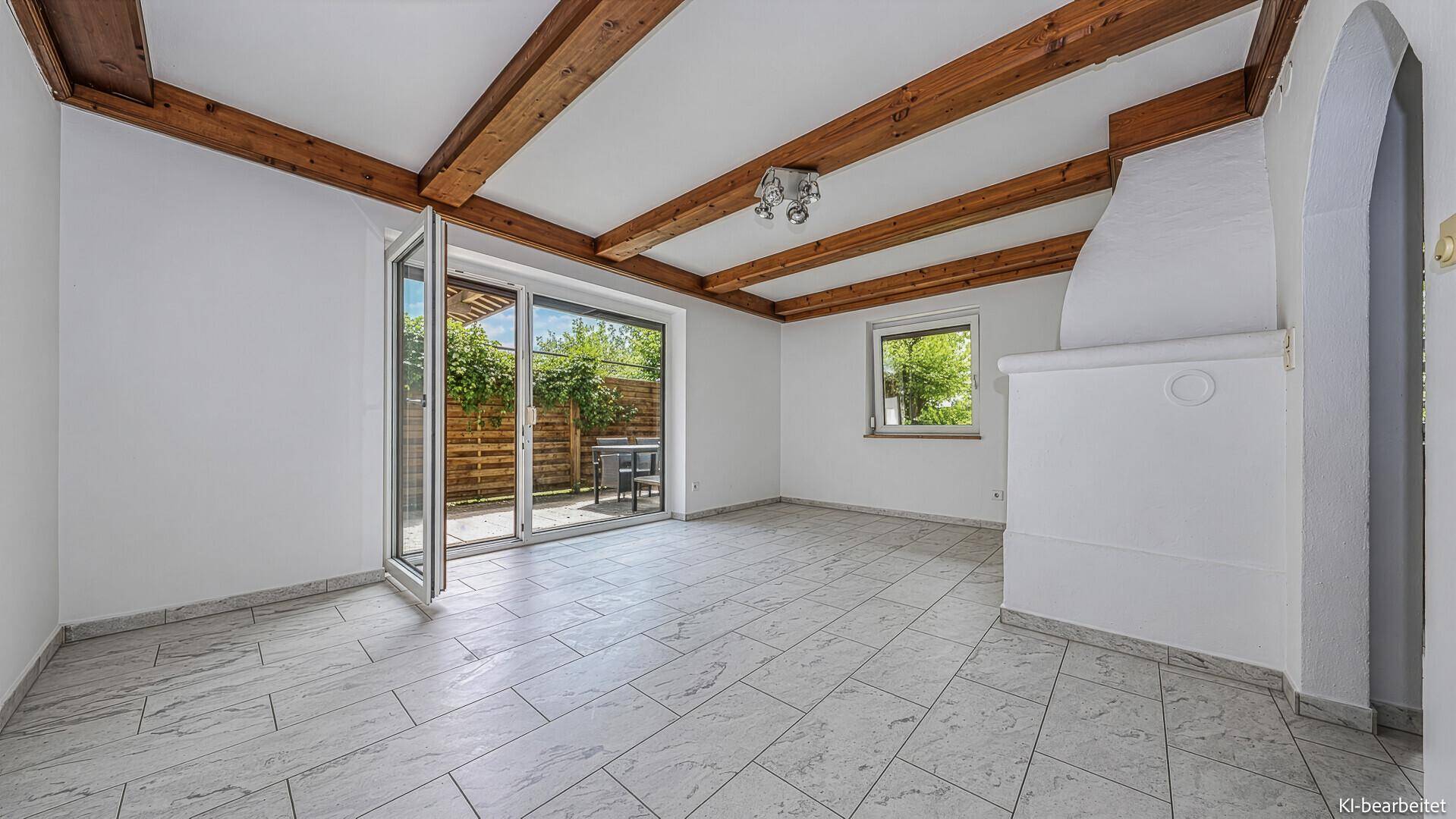 Geräumiges Wohnzimmer mit Fliesenboden, Holzbalken und traditionellem Kachelofen, mit Terrassenzugang.