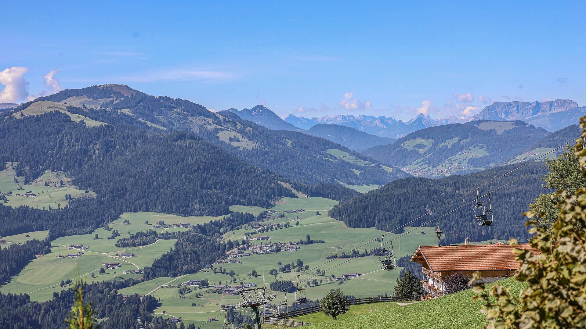 Weitläufiger Panoramablick auf die majestätische Berglandschaft mit grünen Tälern und Skipisten.
