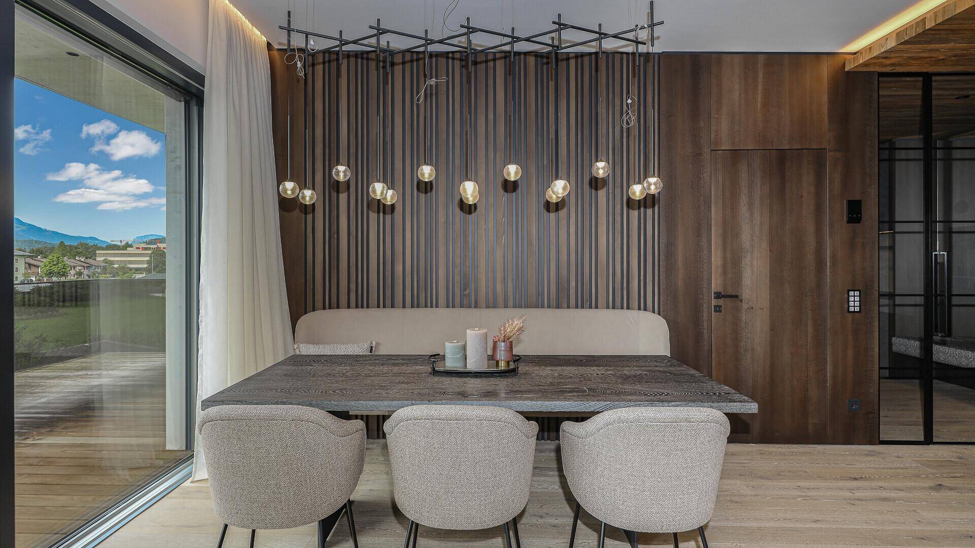 Eleganter Essbereich mit Holztisch, gepolsterter Bank und stilvoller Pendelleuchte.