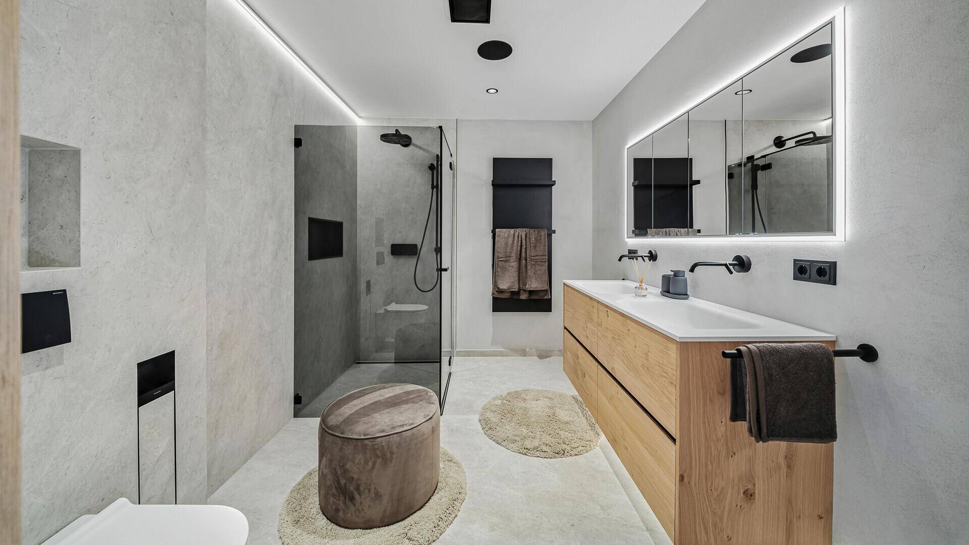 Modernes Badezimmer mit Doppelwaschbecken, beleuchtetem Spiegelschrank und begehbarer Dusche.