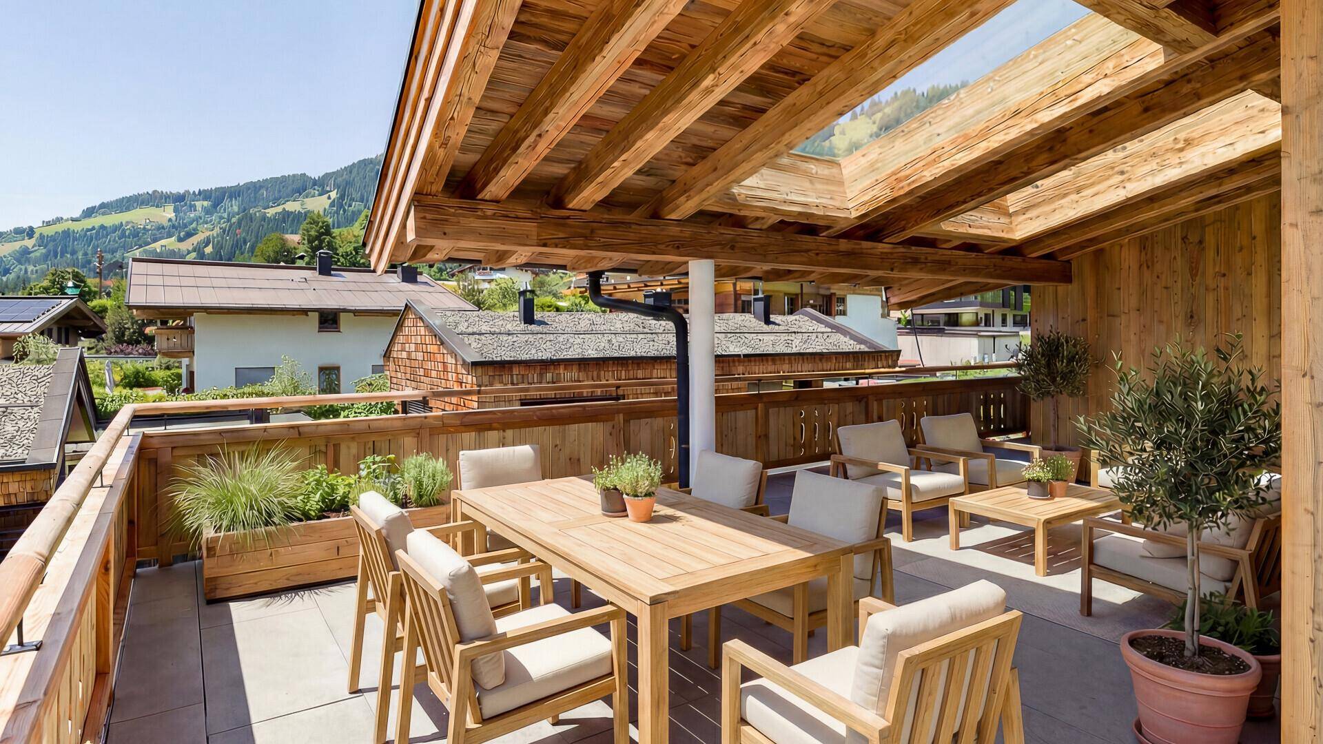 Möblierte Dachterrasse mit Holztisch, Stühlen und Pflanzen, ideal für Entspannung im Freien.