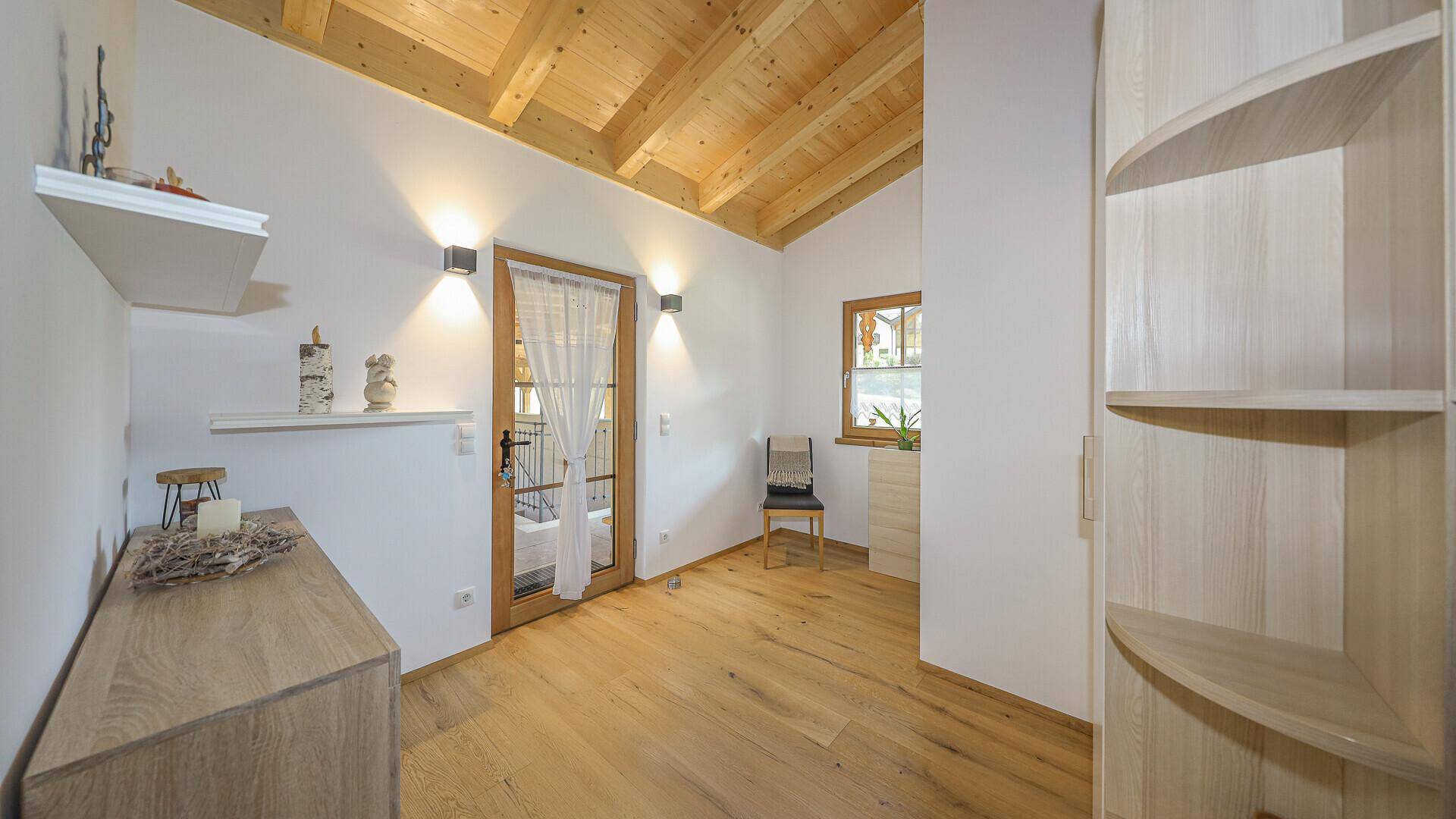 Heller Raum mit Holzfußboden, Kommode und Regalen unter hohen Holzdecken.