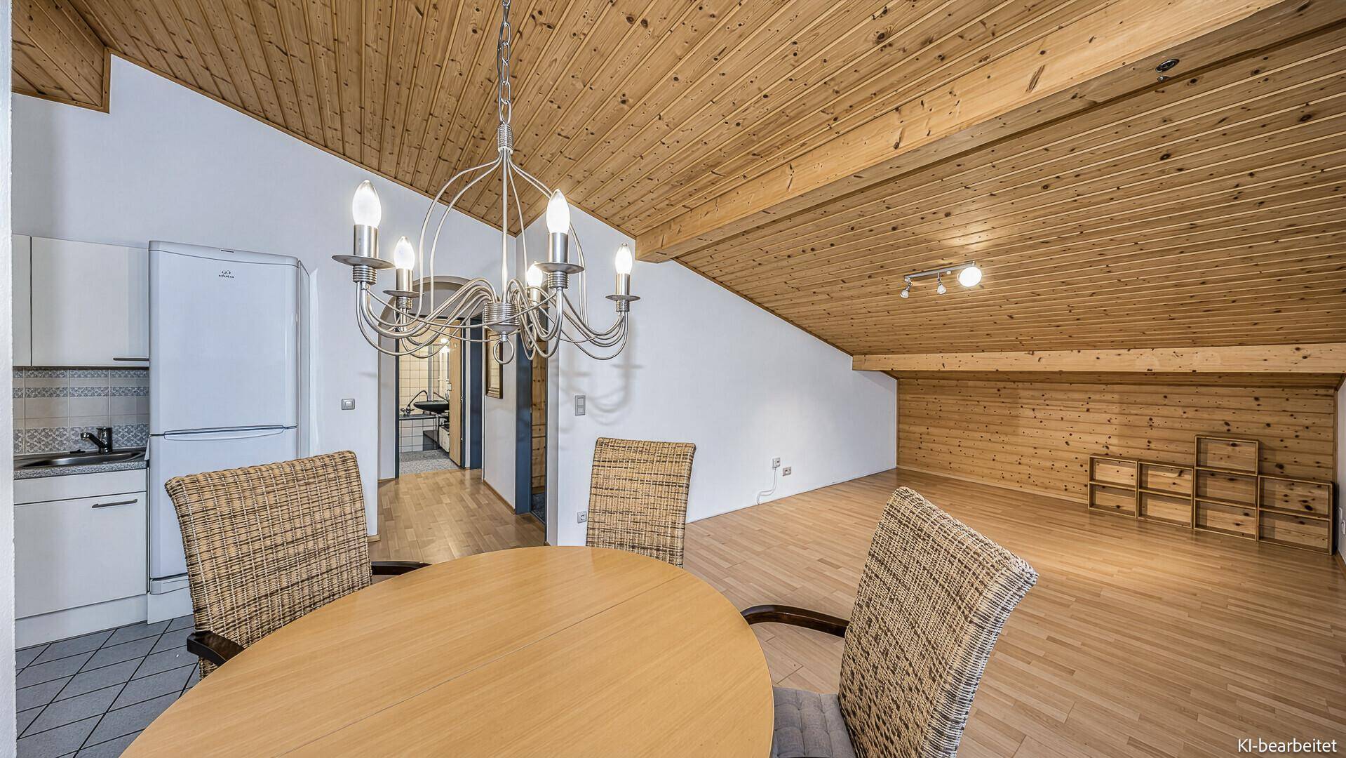 Geräumiger Wohn-Essbereich mit Holzbalkendecke, Parkettboden und kleiner Küchenzeile.