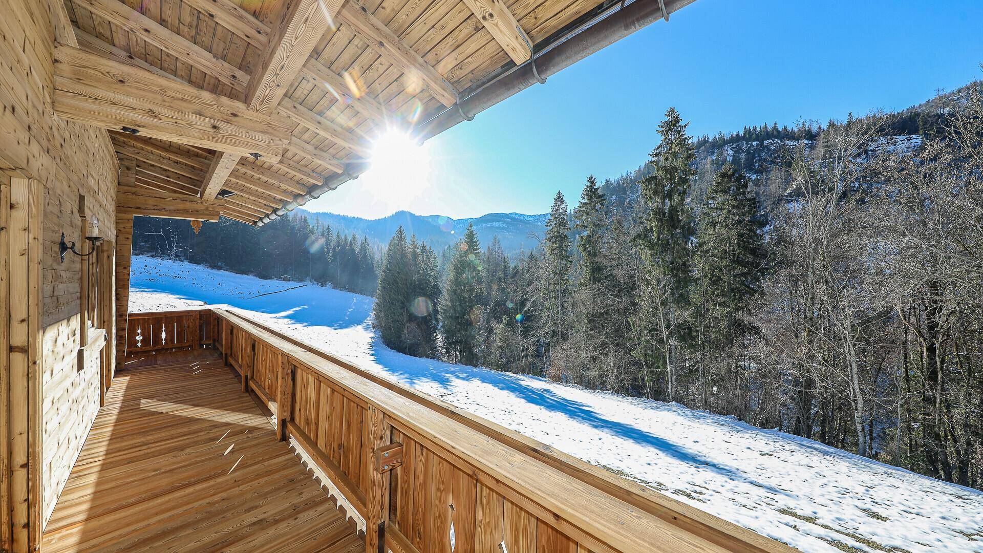Sonniger Holzbalkon mit weitem Blick auf die verschneite Berglandschaft.