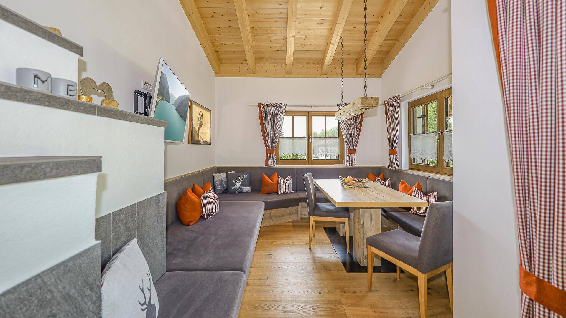 Gemütlicher Essbereich mit großer Eckbank, Holztisch und traditioneller Dekoration unter Holzdecken.