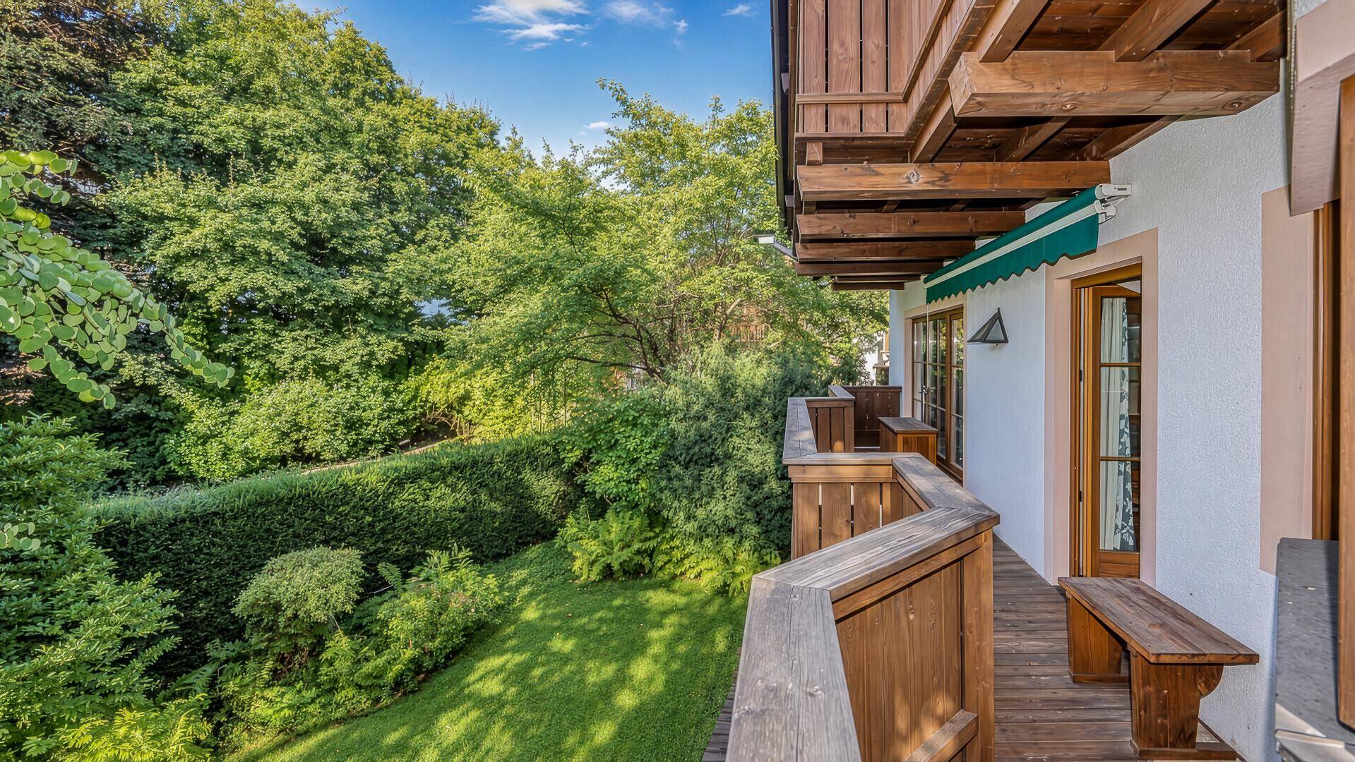 Geräumiger Holzbalkon mit Blick auf den grünen Garten und die umliegende Natur.