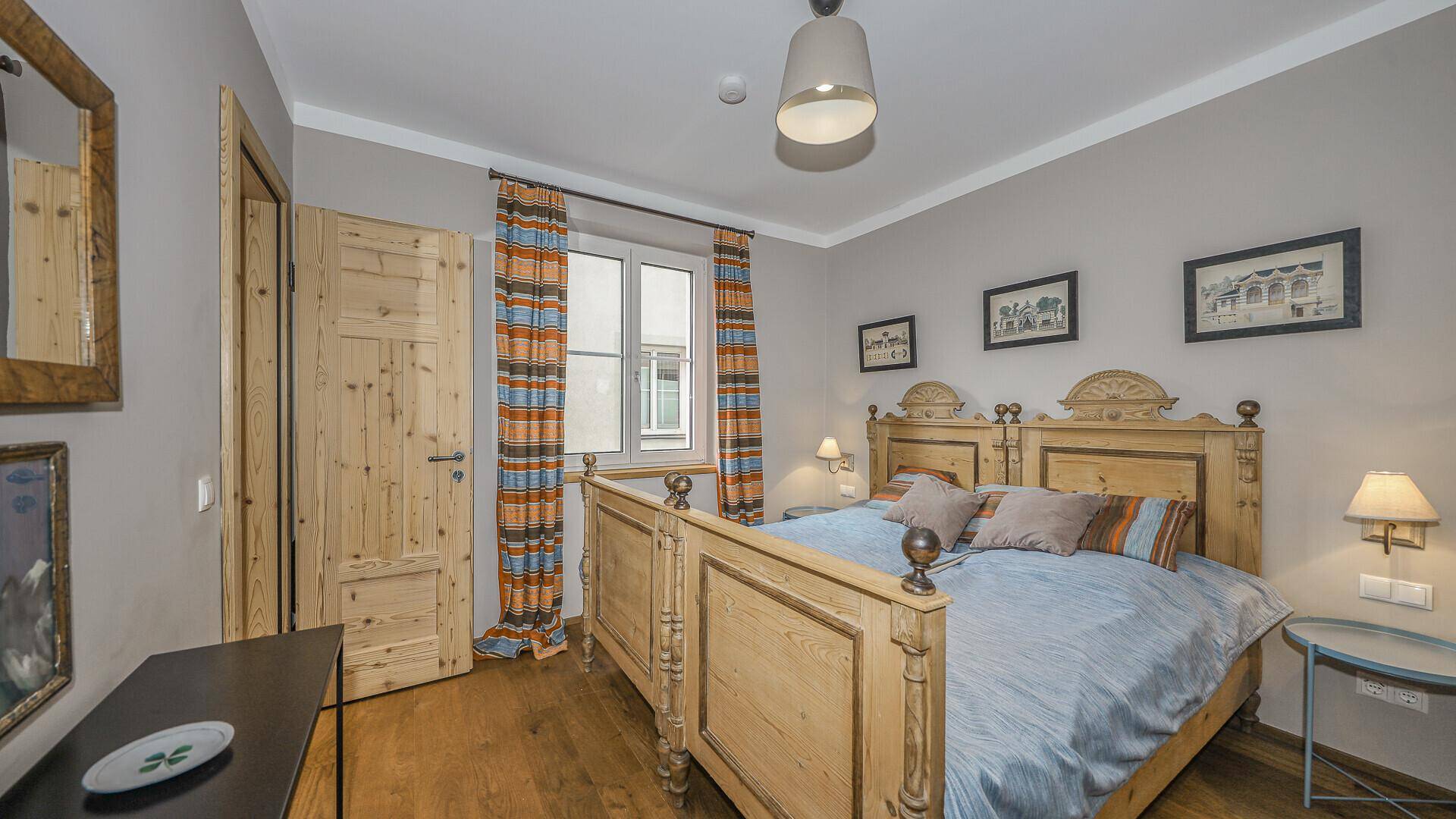 Gemütliches Schlafzimmer mit traditionellem Holzbett und Holzboden im alpinen Stil.