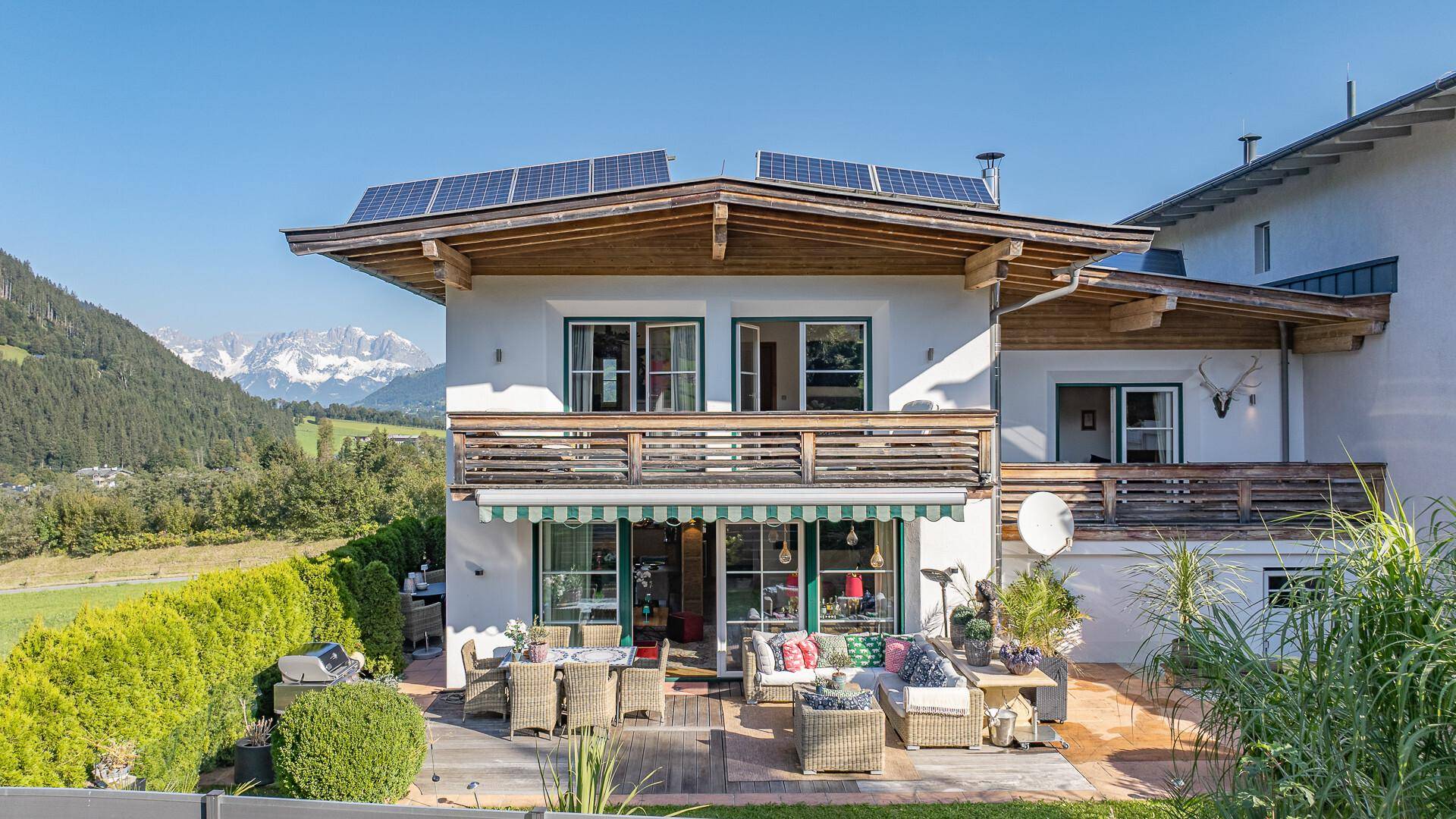 Charmantes Haus mit Sonnenterrasse, Gartenmöbeln und Photovoltaikanlage auf dem Dach mit Bergblick.