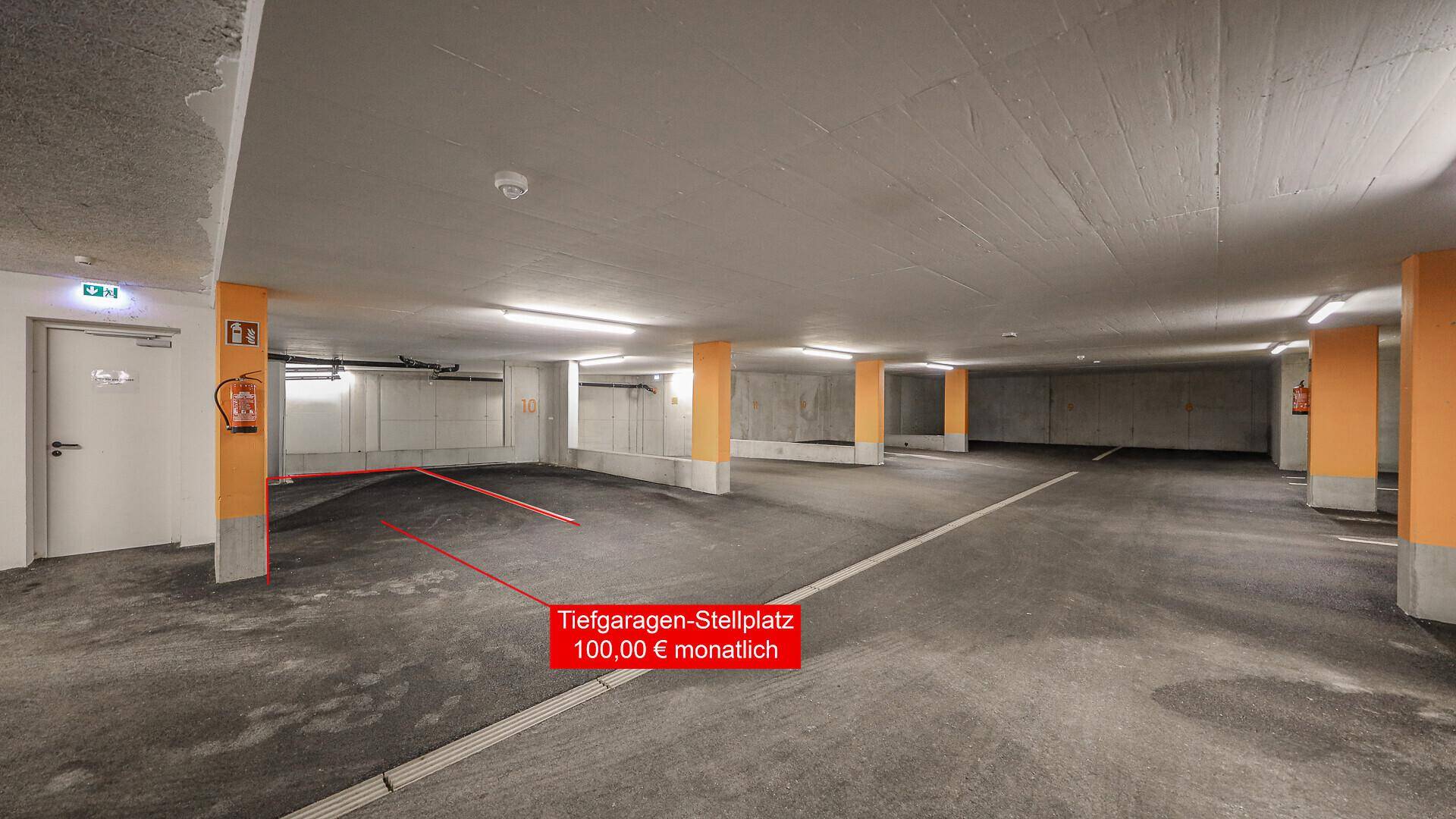 Tiefgarage mit Betonboden und orangefarbenen Säulen, ein Stellplatz ist rot markiert.