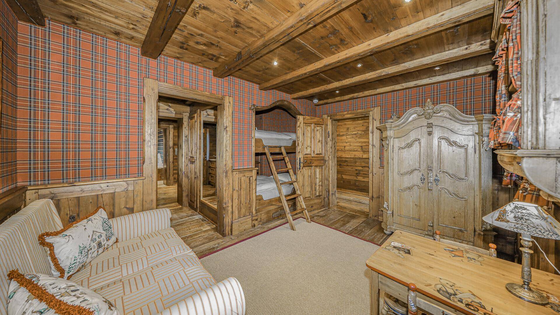 Kinderzimmer mit Etagenbetten aus Holz, karierter Tapete und rustikalen Möbeln.