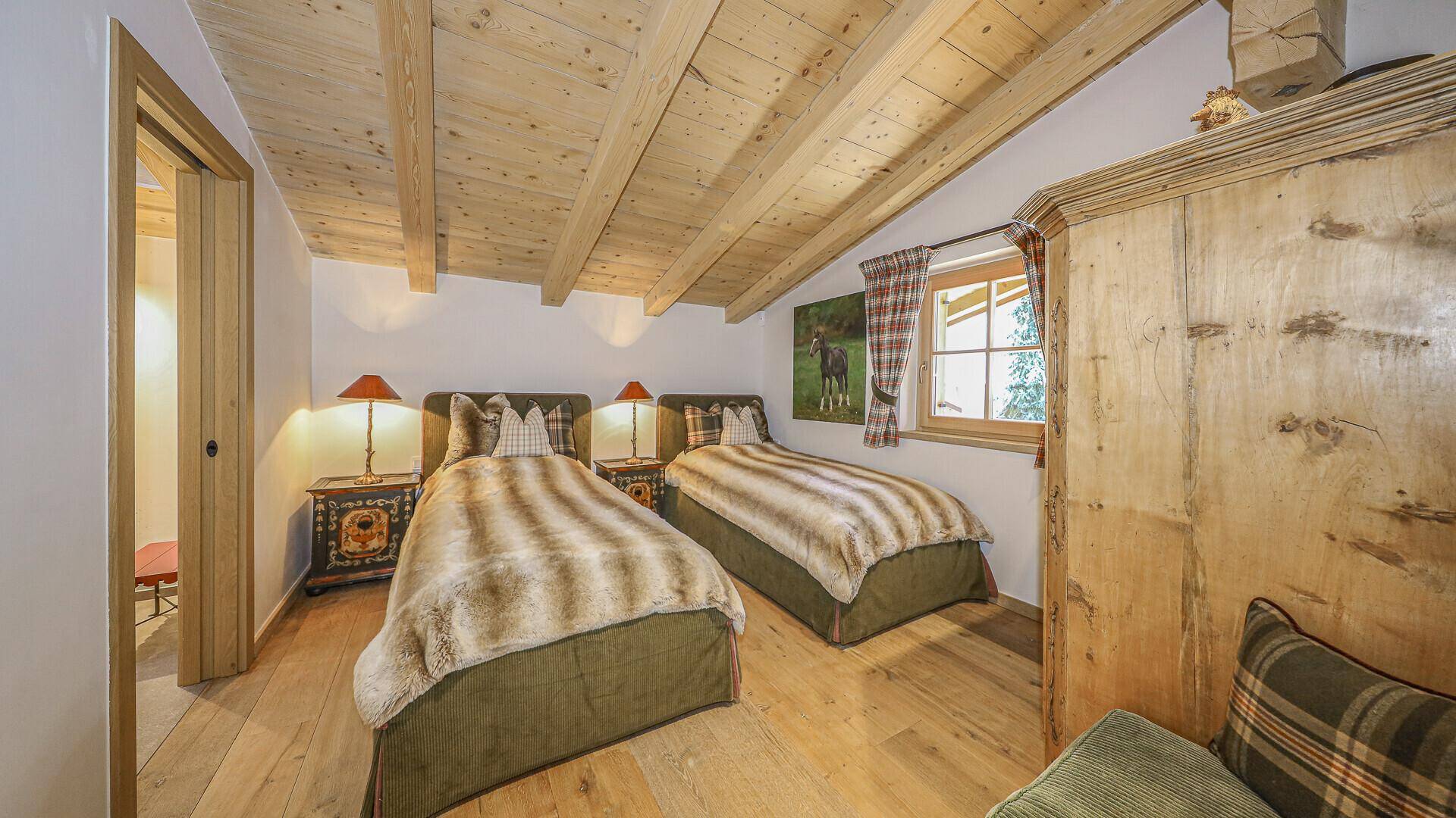 Gemütliches Schlafzimmer mit zwei Einzelbetten, Holzbalkendecke und traditionellem Holzschrank.