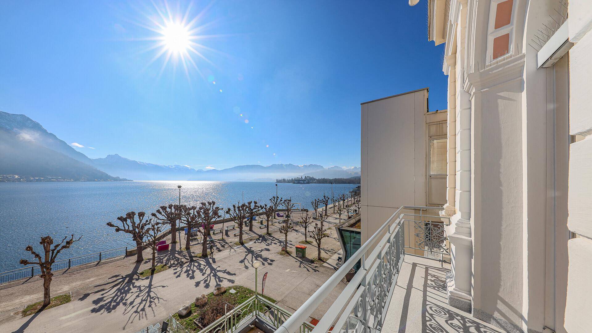 Sonniger Balkon mit schmiedeeisernem Geländer und atemberaubendem Blick auf den See und die Berge.