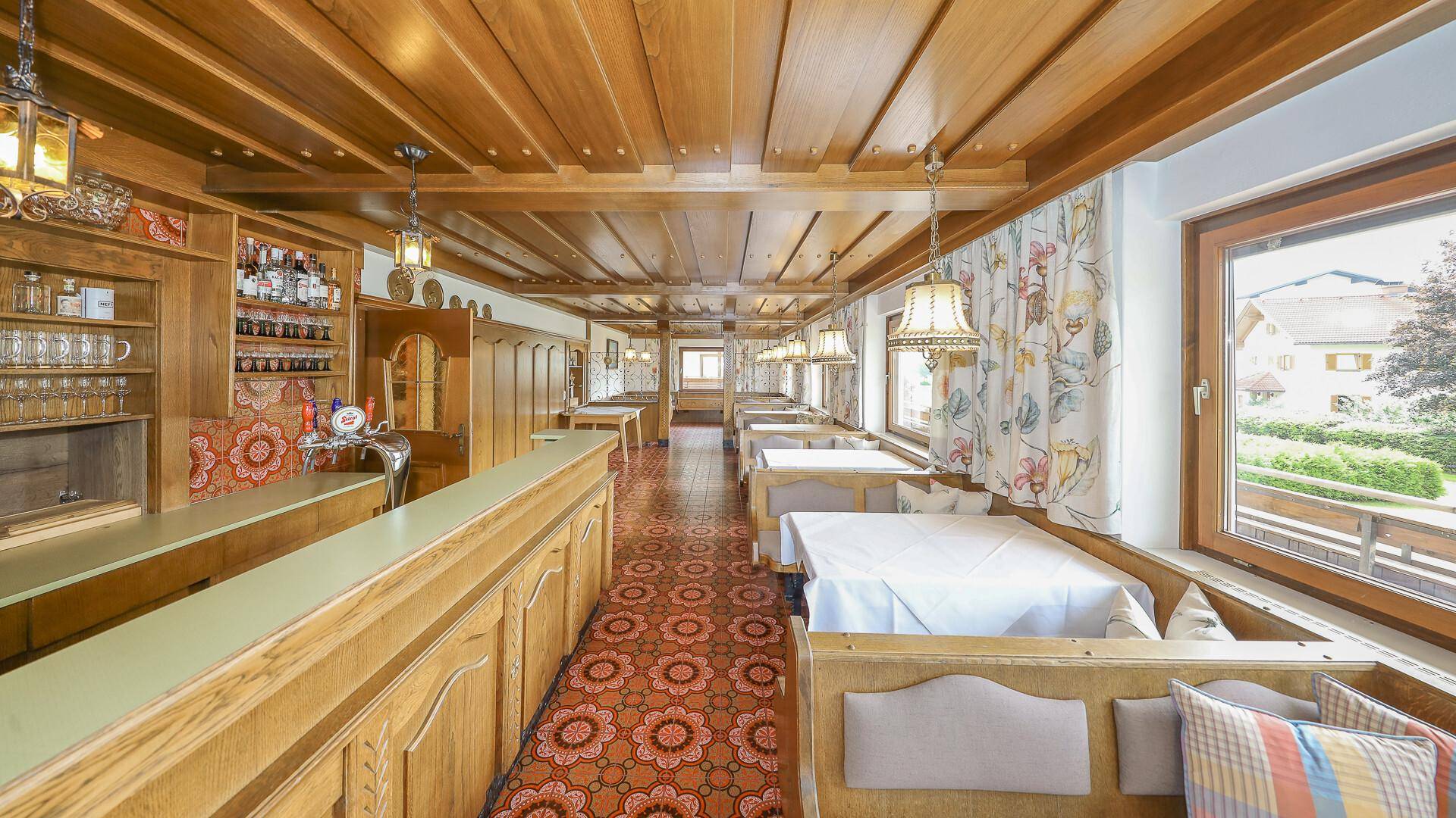 Geräumiger Speisesaal mit traditioneller Holzeinrichtung, vielen Tischen und einer Bar, ideal für größere Gruppen.