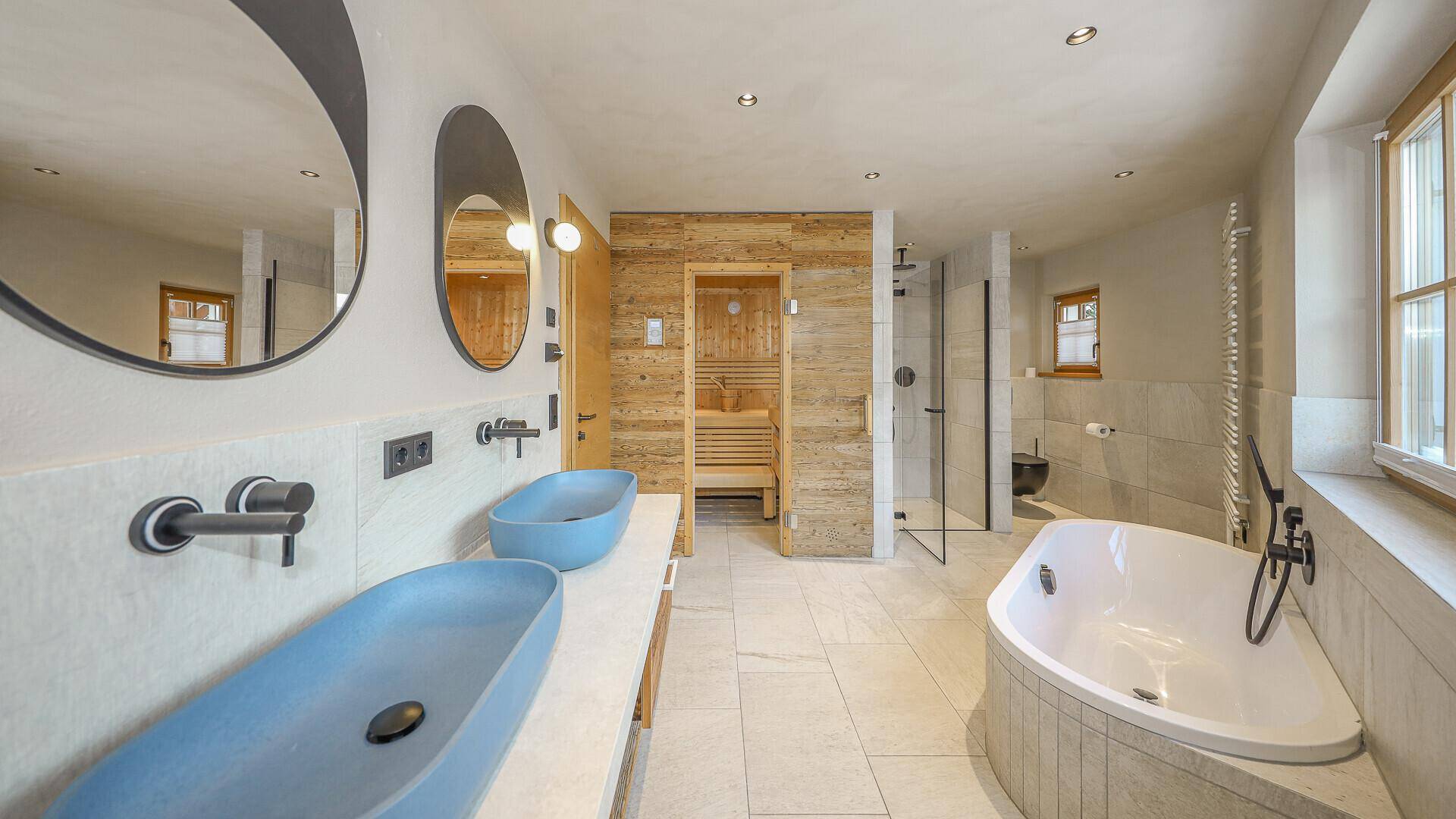 Luxuriöses Badezimmer mit Doppelwaschbecken, Badewanne, Dusche und integrierter Sauna.