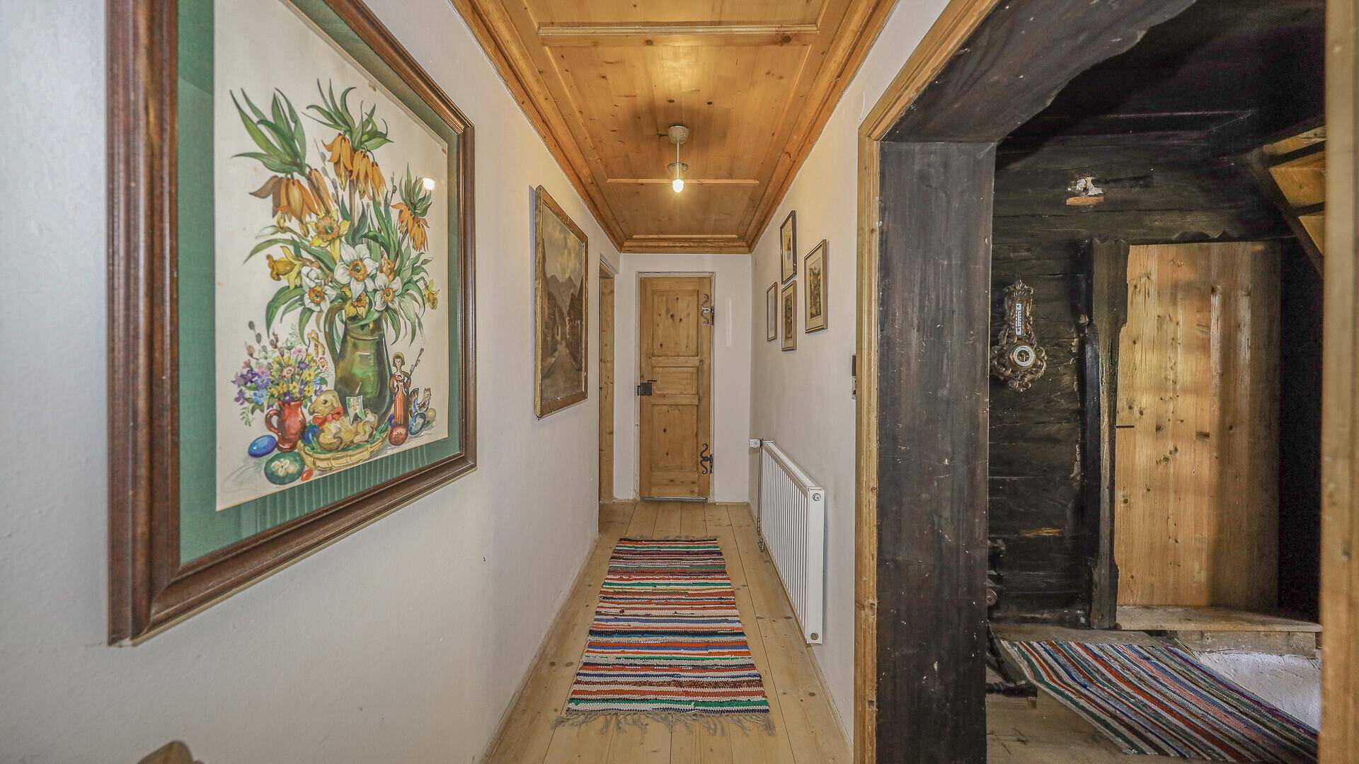 Traditioneller Flur im Originalzustand mit Holzboden, Holzdecke und rustikalen Gemälden.
