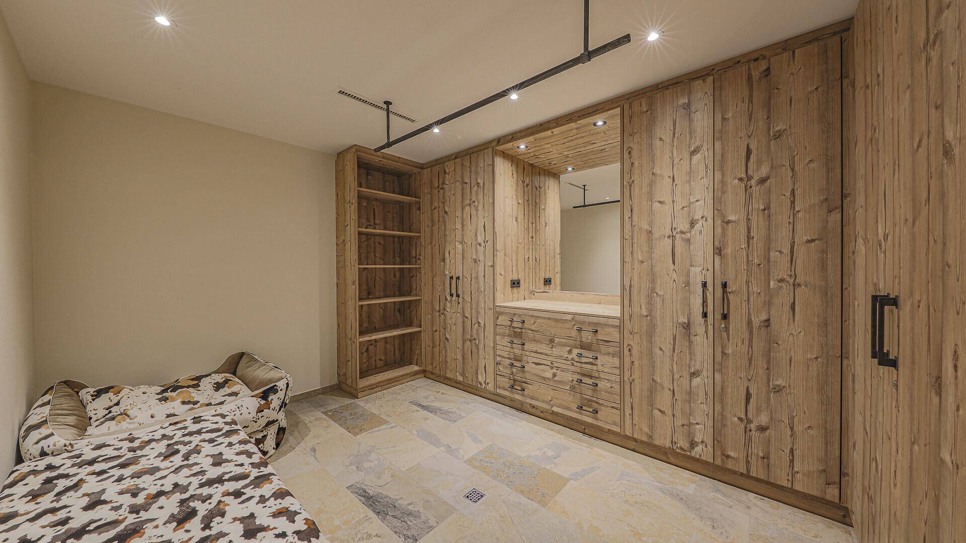 Begehbarer Kleiderschrank mit maßgefertigten Holzschränken und Spiegelbereich.