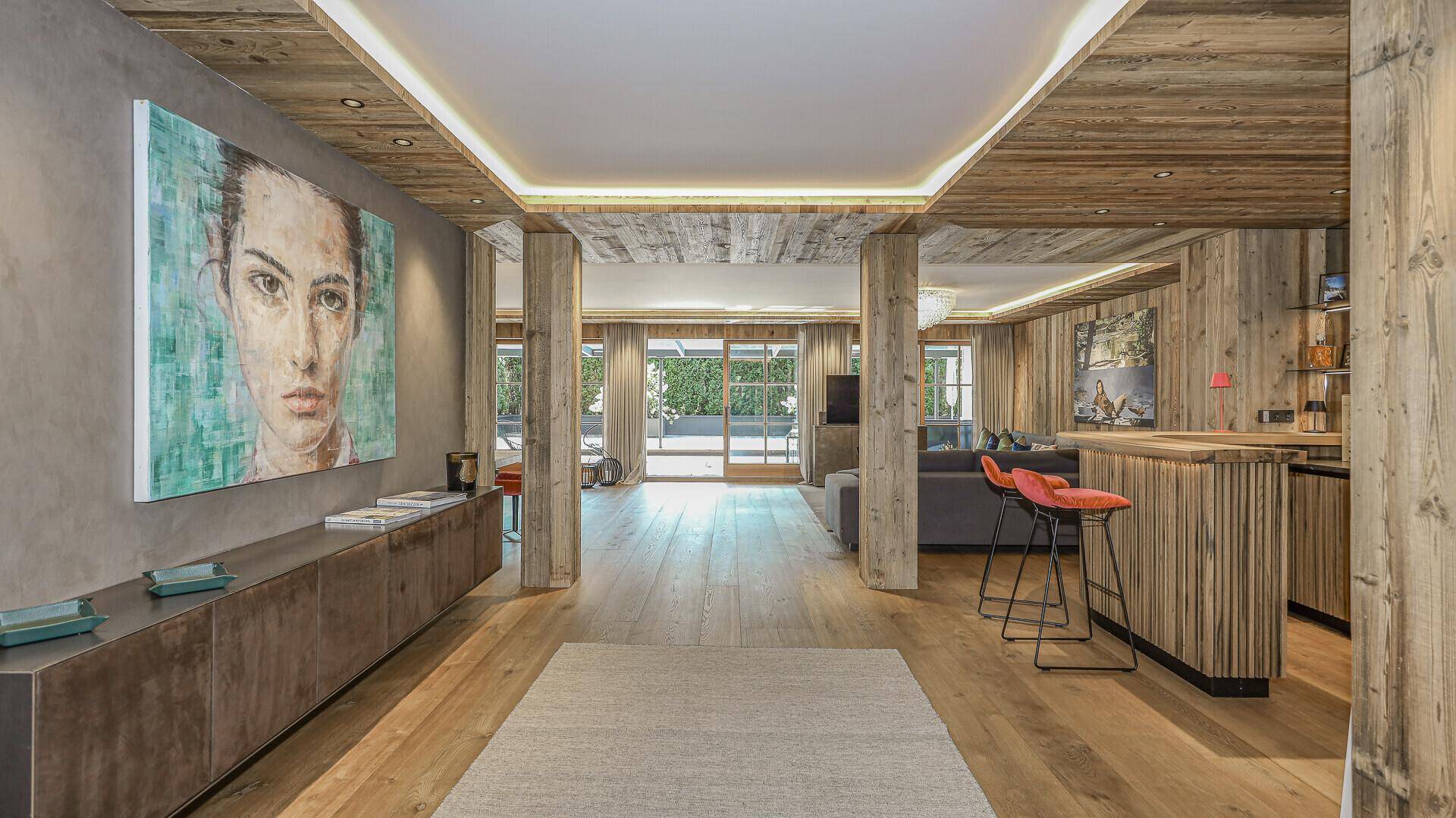 Geräumiger Eingangsbereich mit Holzwänden, moderner Kunst und einer stilvollen Bar im Hintergrund.