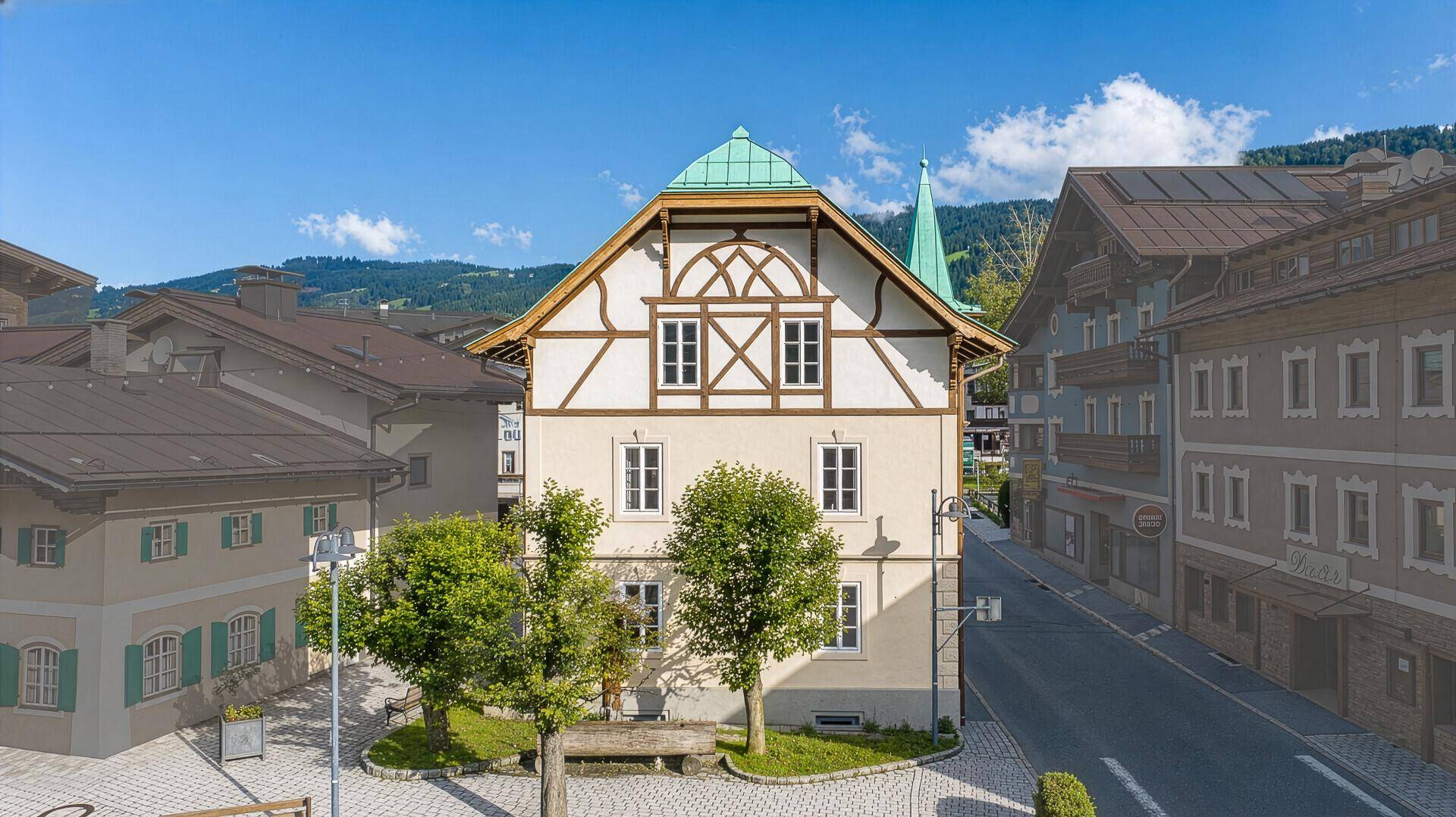 Traditionelles Gebäude im alpinen Stil mit grünem Dach und Fachwerkelementen in einer Berglandschaft.