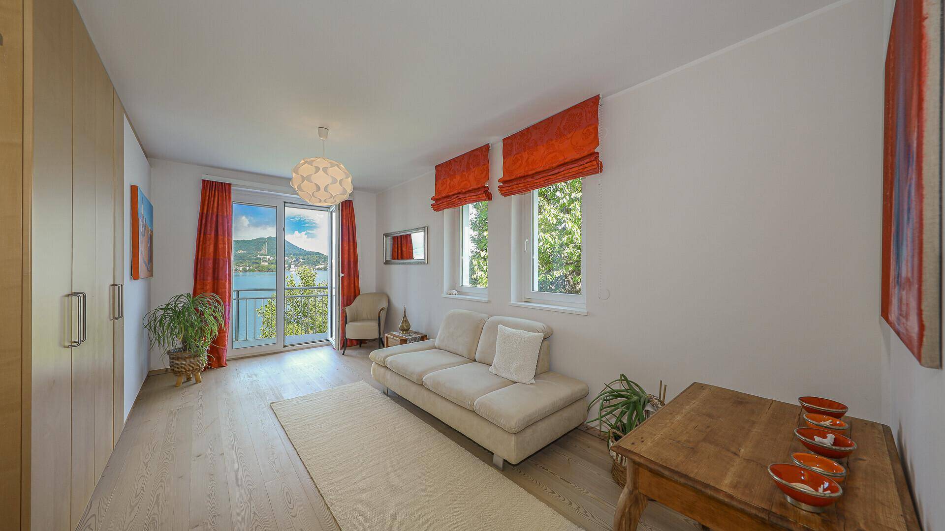 Gemütliches Schlafzimmer mit Sofa, Einbauschränken und Balkonzugang mit Seeblick.