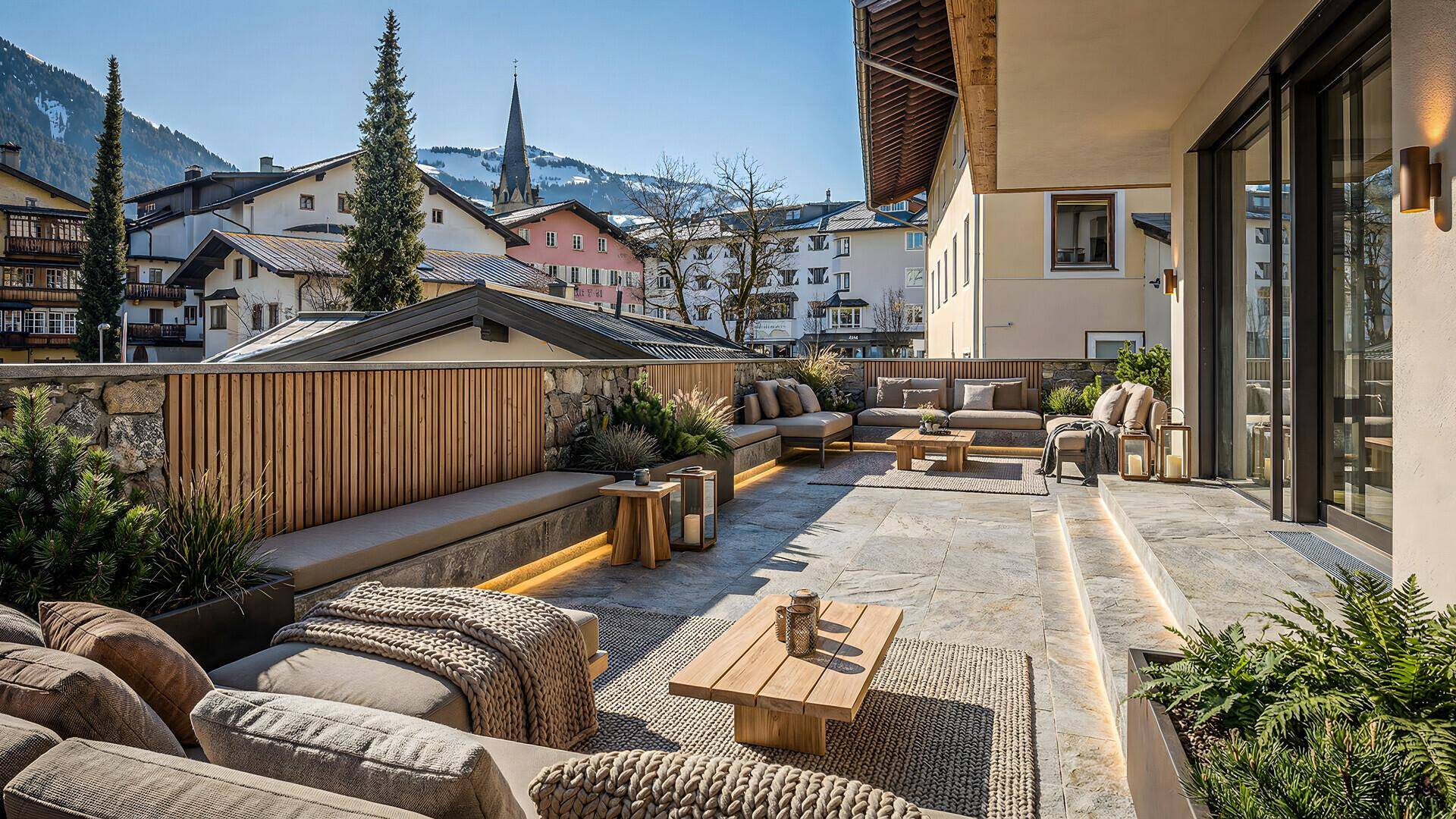 Großzügige Sonnenterrasse mit bequemen Lounge-Möbeln und Panoramablick auf das Dorf und die Berge.