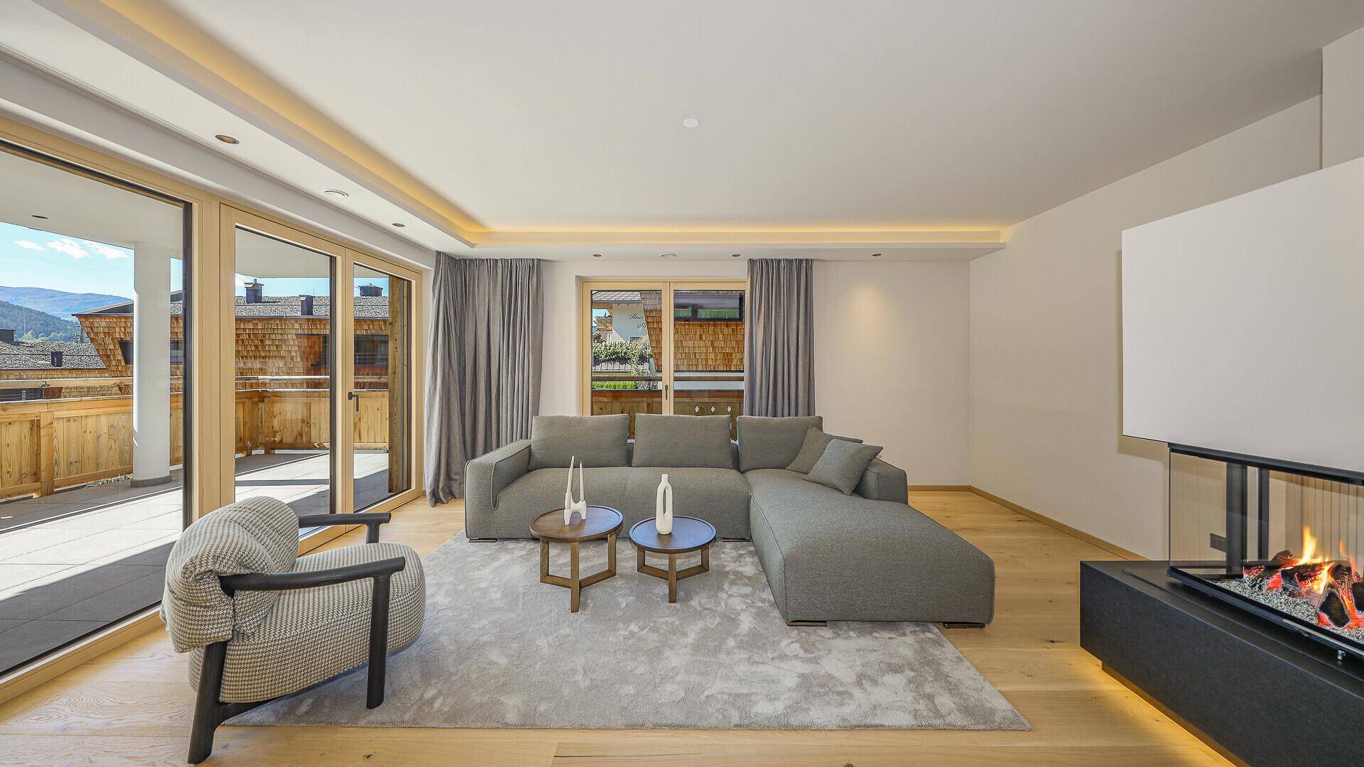 Gemütliches Wohnzimmer mit großem Sofa, Kamin und direktem Zugang zur Terrasse.