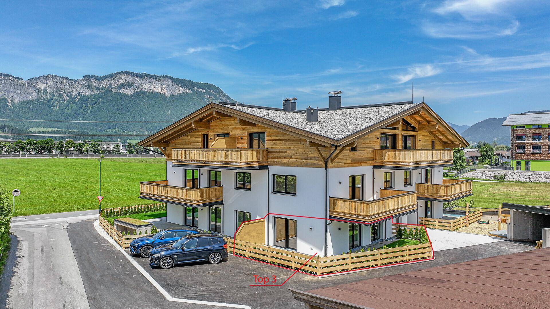 Modernes Mehrfamilienhaus im alpinen Stil mit Balkonen und Bergblick.