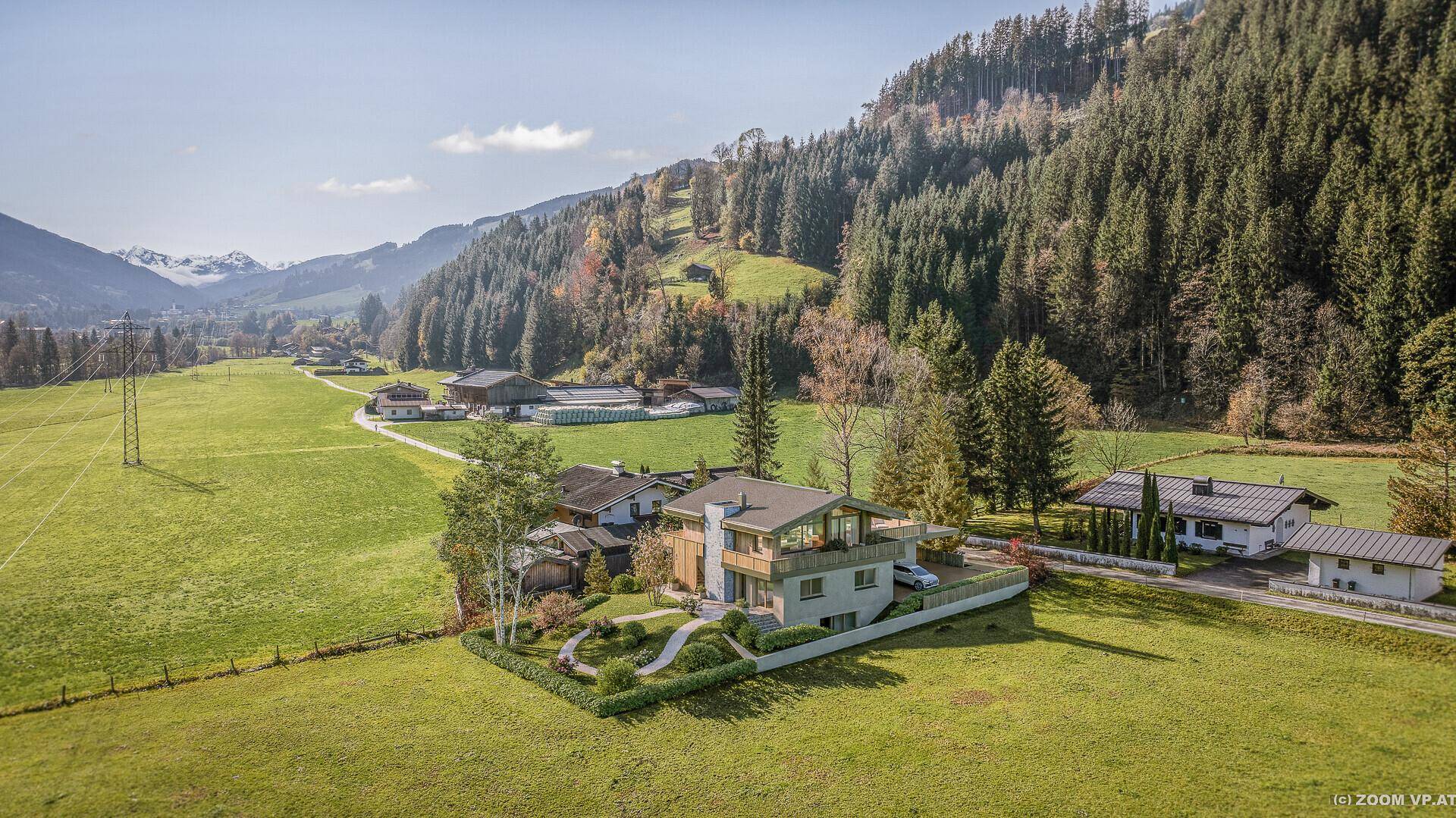 Weitläufige Ansicht des Anwesens in einer sonnigen Berglandschaft mit grünen Wiesen und dichten Wäldern.