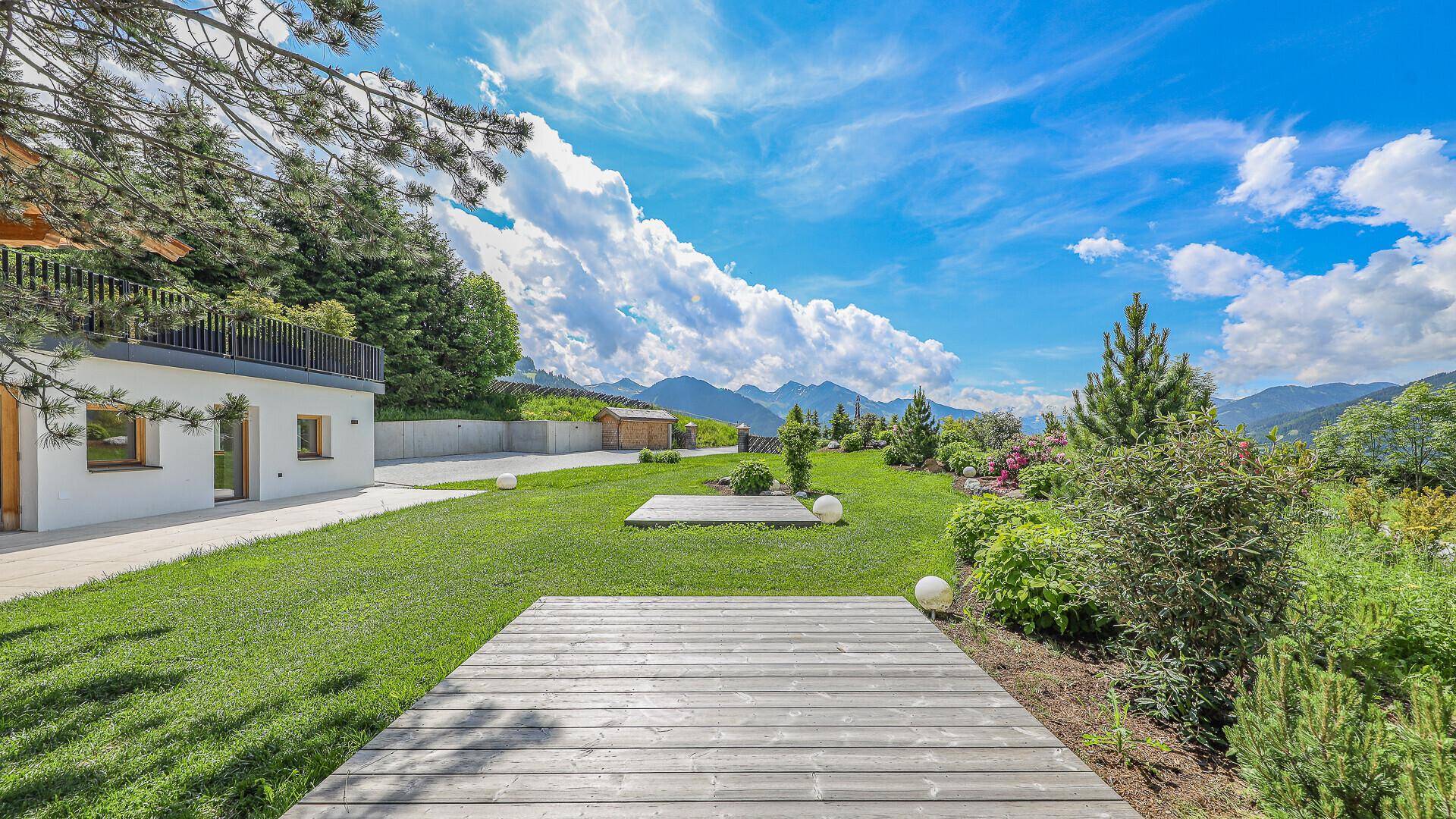 Weitläufiger Garten mit Holzdecks, grünen Büschen und beeindruckendem Bergblick.