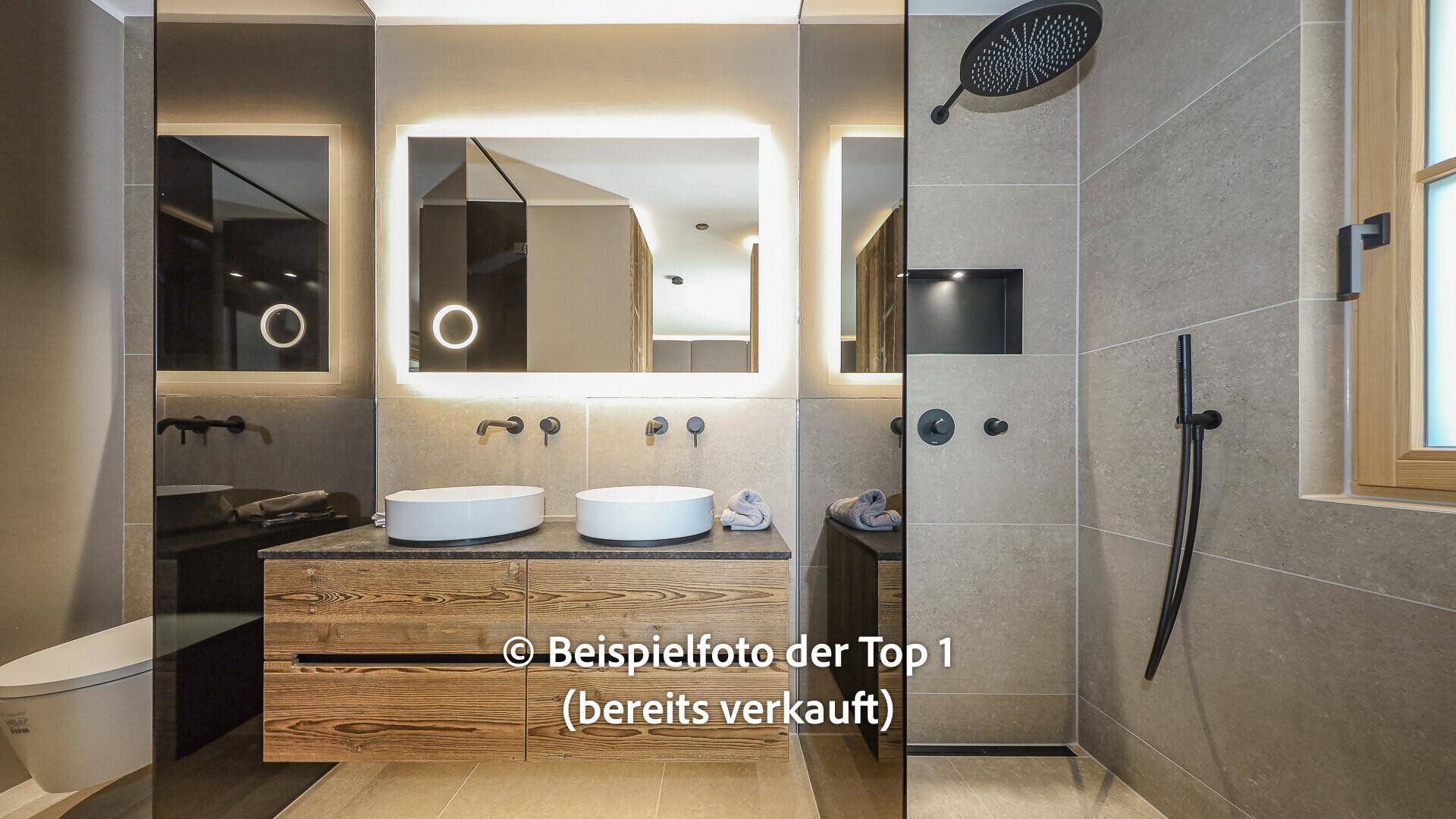 Elegantes Badezimmer mit Doppelwaschbecken, beleuchtetem Spiegel und großer begehbarer Dusche.
