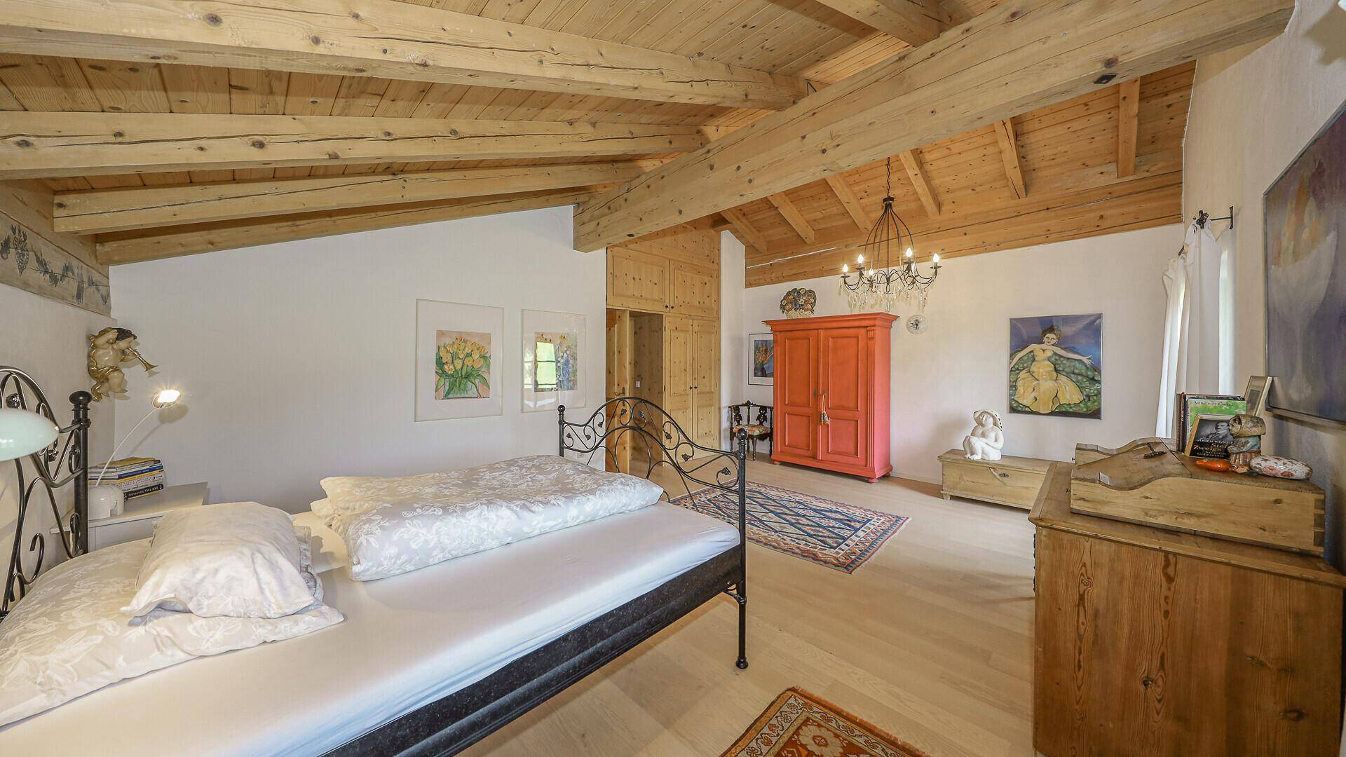 Helles Schlafzimmer mit Holzbalkendecke, Holzboden und traditionellen Möbeln.