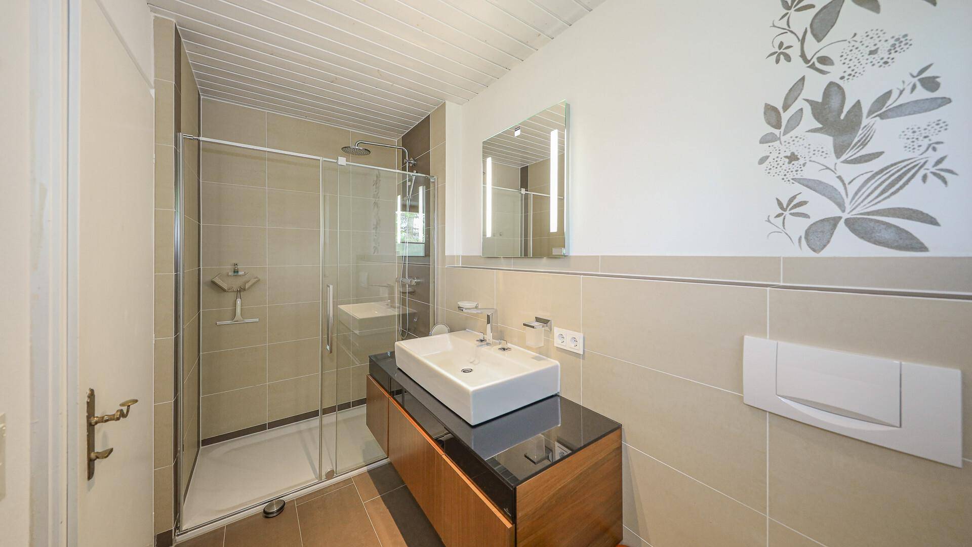 Modernes Badezimmer mit Duschkabine, Waschbecken und Wand-WC.