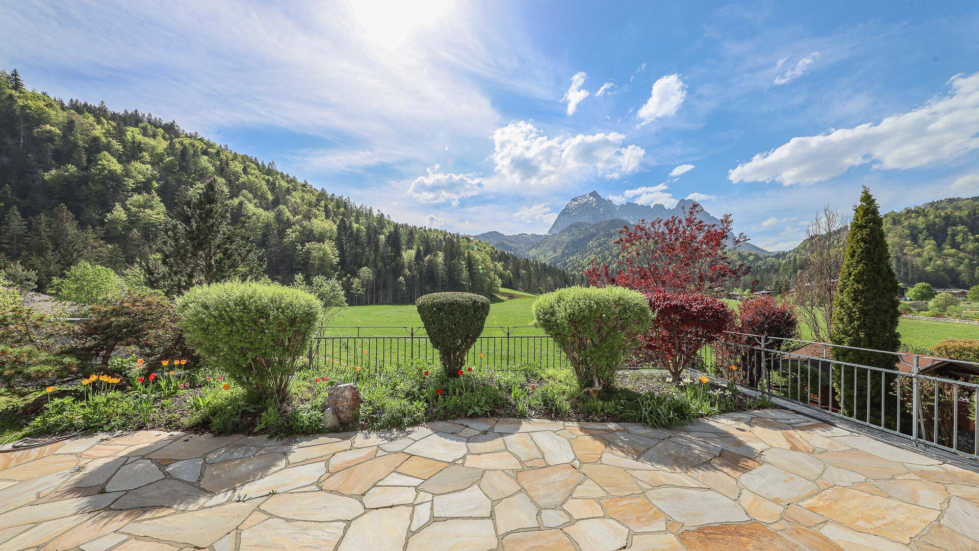 Großzügige Steinterrasse mit Garten und weitem Blick in die Natur und auf die Berge.