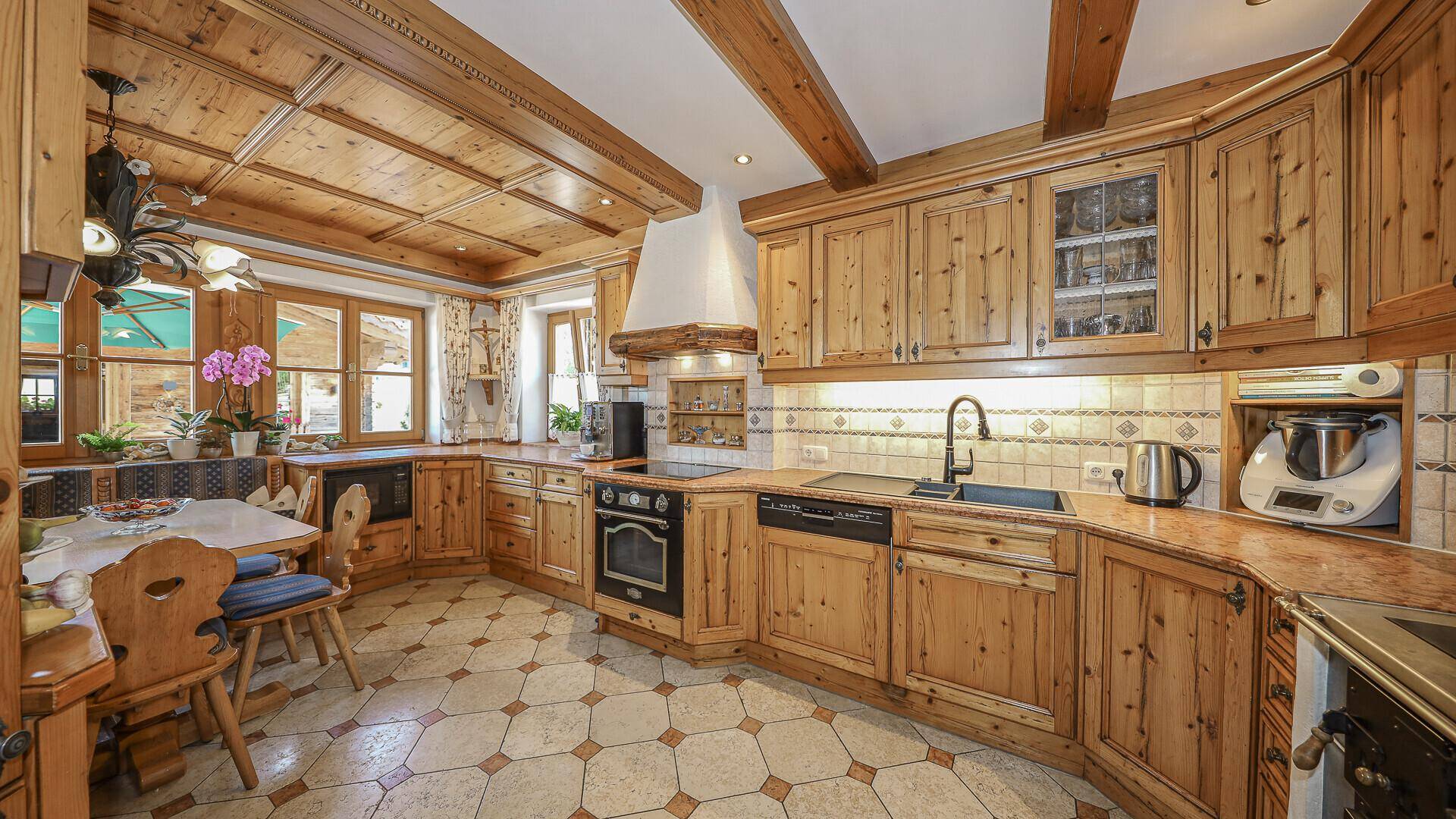 Rustikale Küche im Landhausstil mit Holzeinbauten, Fliesenboden und gemütlicher Essecke.