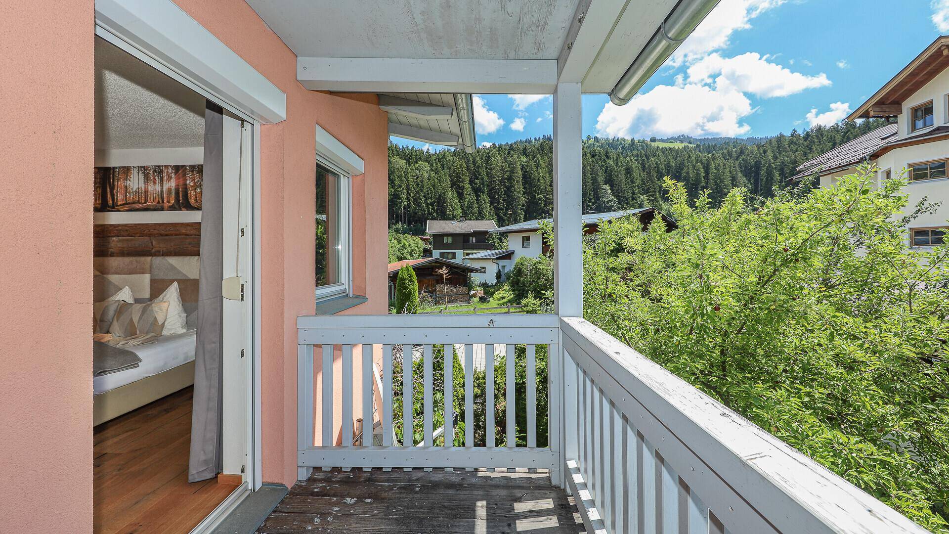 Heller Balkon mit weißem Geländer und Blick auf grüne Bäume und die Umgebung.