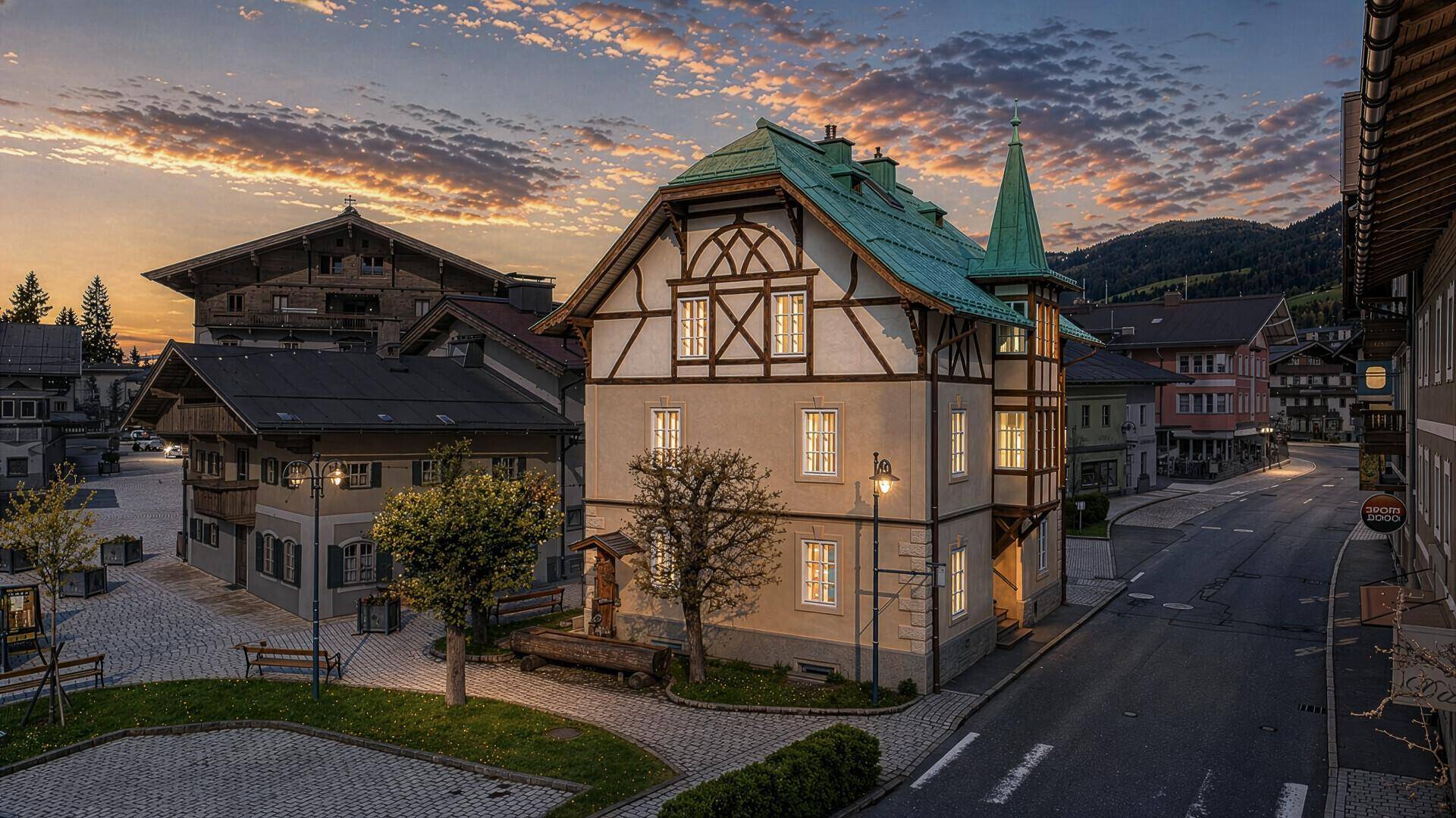 Traditionelles Gebäude im alpinen Stil bei Sonnenuntergang mit beleuchteten Fenstern und Bergkulisse.