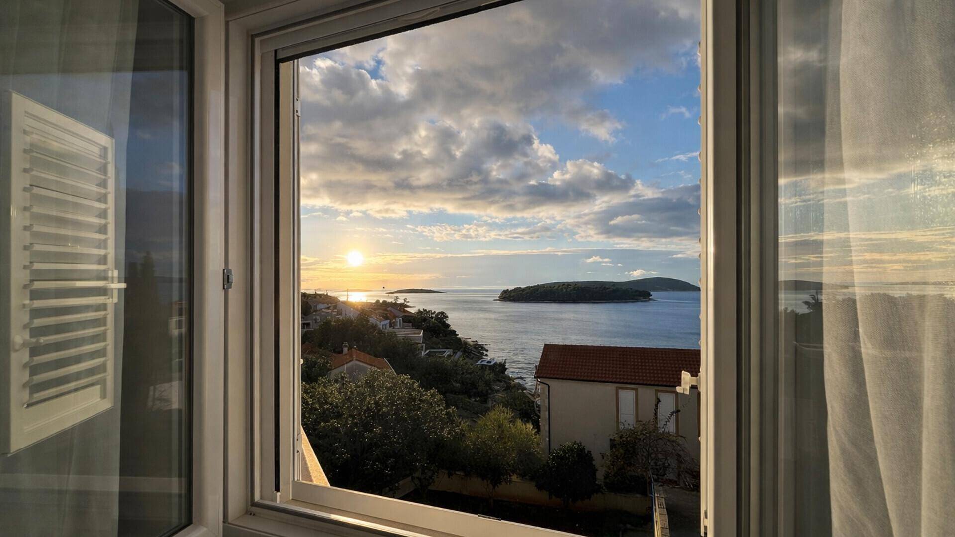 Blick aus dem Fenster auf das Meer und die Inseln bei einem wunderschönen Sonnenuntergang.