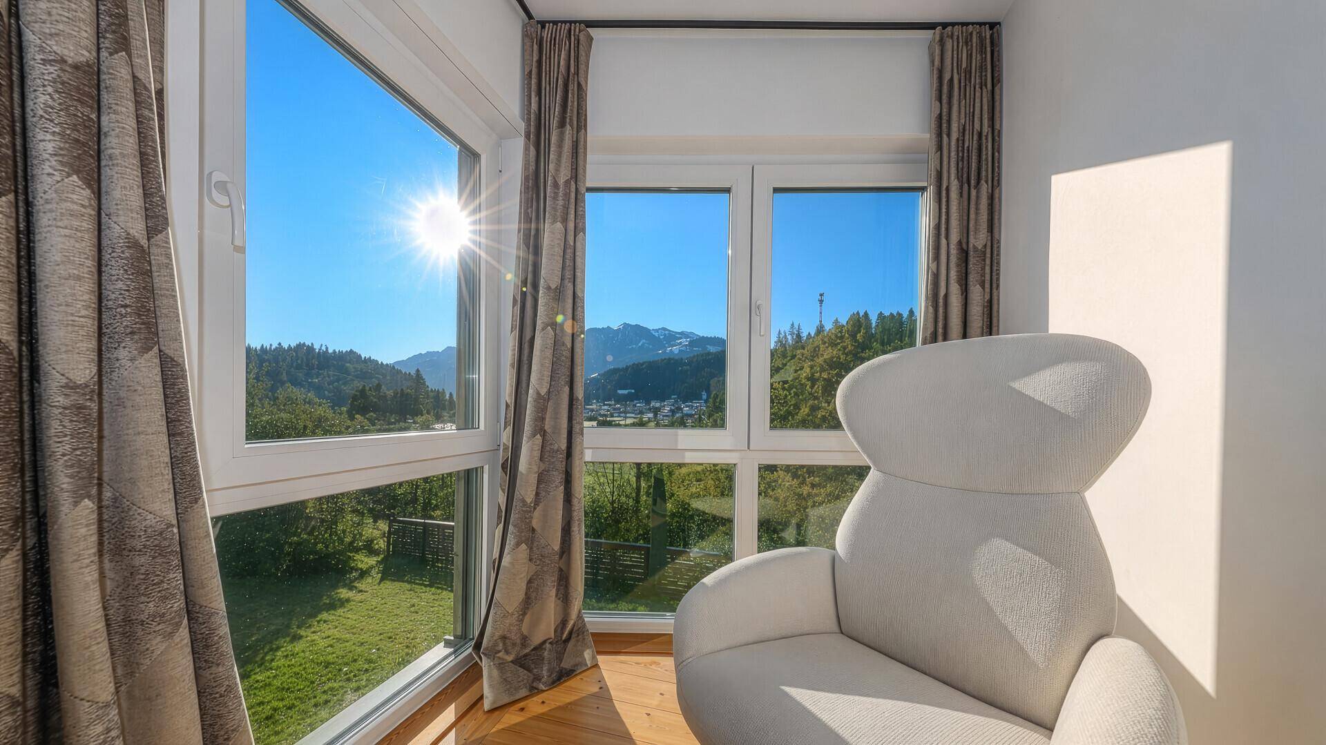 Sonnige Ecke im Schlafzimmer mit bequemem Sessel und weitem Blick auf die beeindruckende Bergwelt.