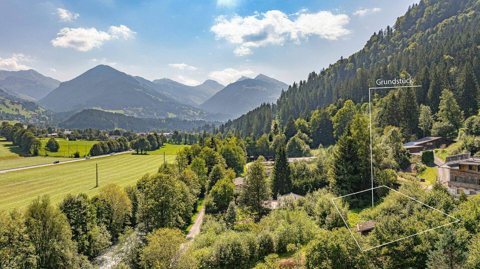 Weitläufige Landschaftsaufnahme eines Tals mit Bergen, Feldern und einem markierten Grundstück.