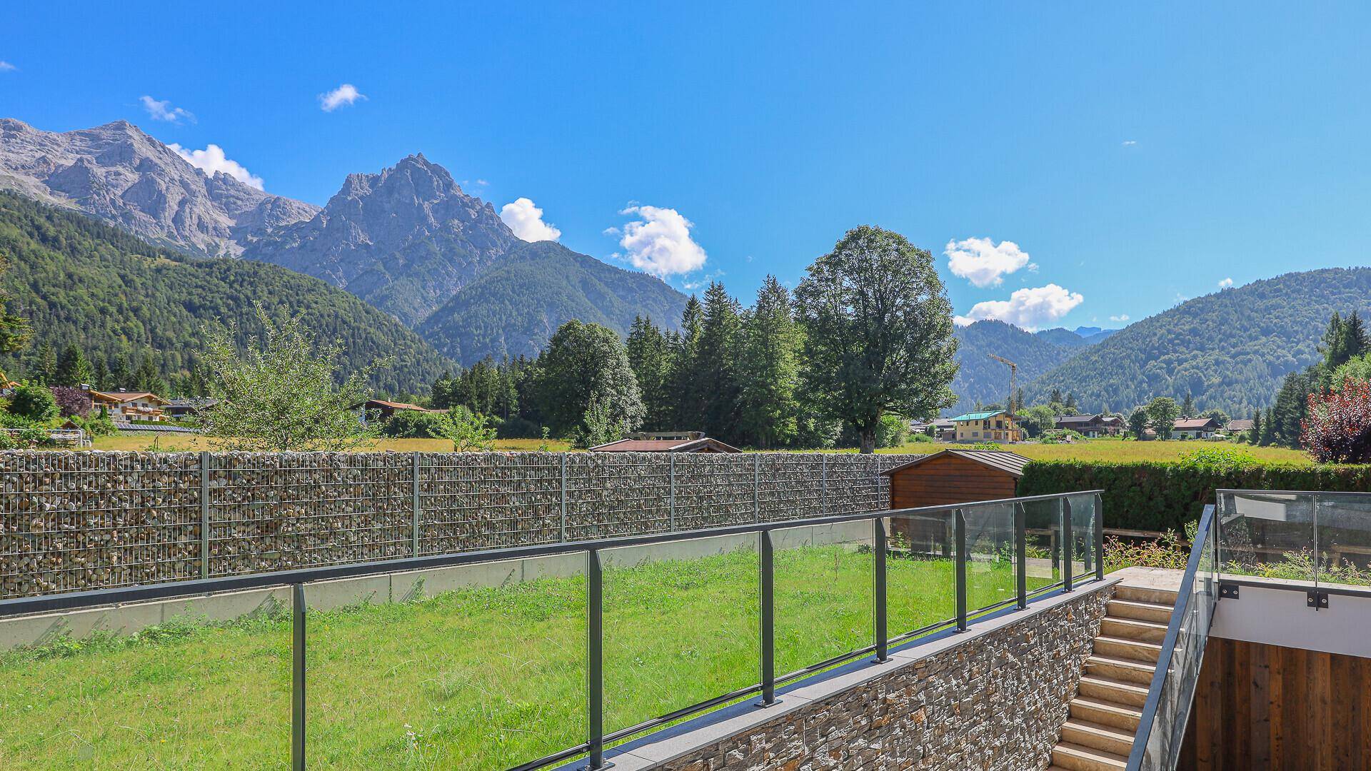 Grüner Gartenbereich mit Treppenzugang und weitem Blick auf die umliegende Berglandschaft.